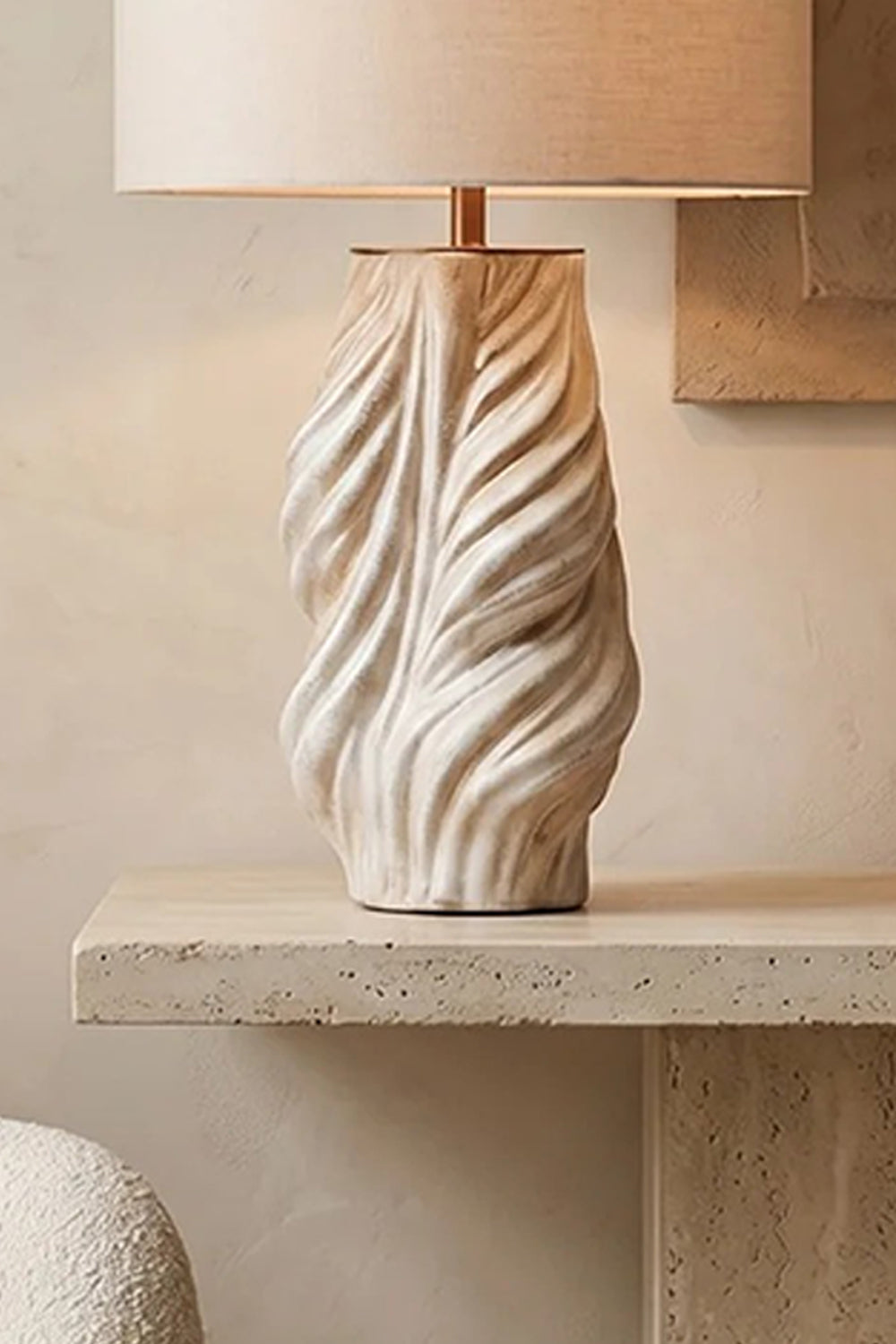 Adara Sculptural Ceramic Table Lamp | Ceramic, Fabric | Close-up side view showcasing the organic, deeply carved wavy ridges of the cream sculptural ceramic base resting on stone | Detail shot | Samu Lamp