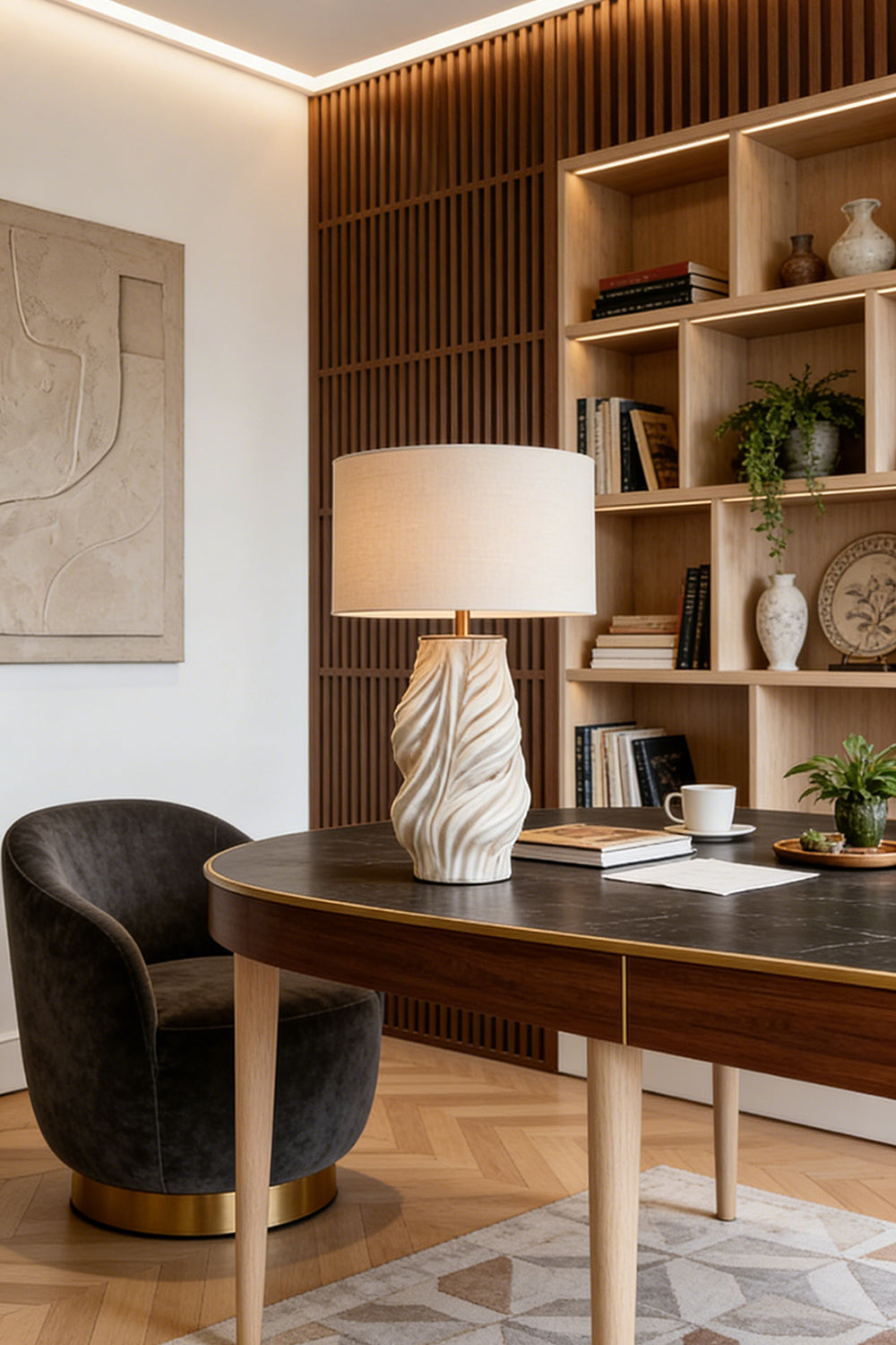 Adara Sculptural Ceramic Table Lamp | Ceramic, Fabric | Standing on a sleek executive writing desk next to a luxury black velvet chair in a modern home office with open shelving | Samu Lamp