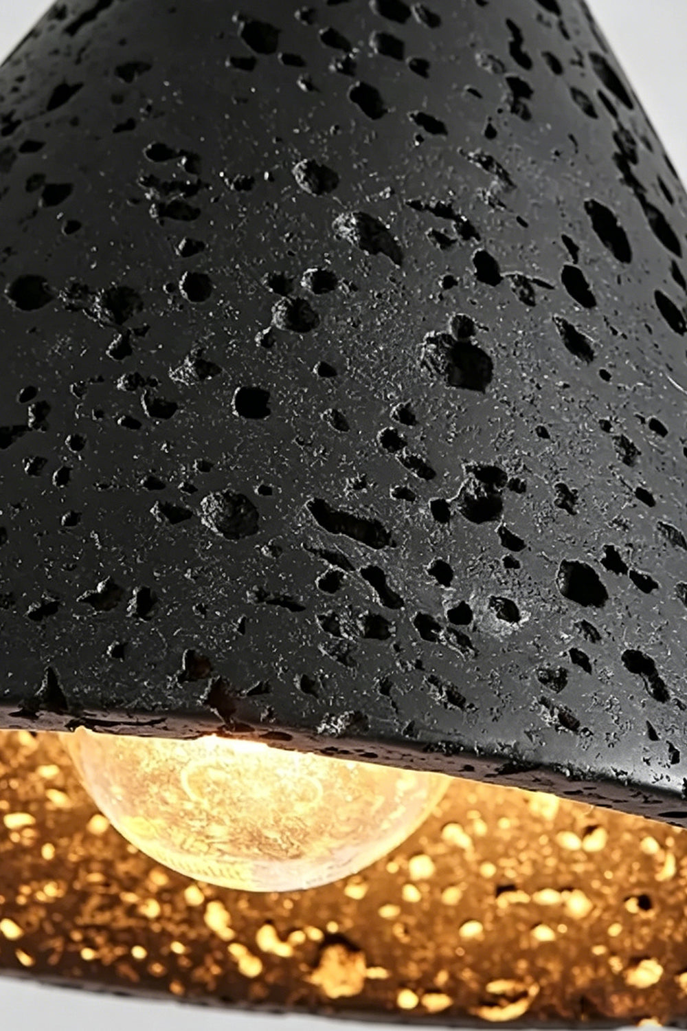 Aethel Core Detail Shot | Black Travertine, Metal | Close-up of porous texture and lit bulb | Samu Lamp