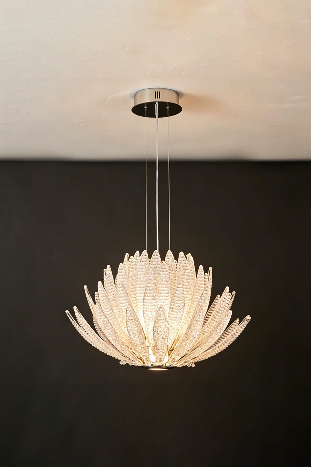 Helios Agave Glass Starburst Chandelier | Glass, Metal | Clear glass variant fully lit against a black background, highlighting its brilliant white light | Isolated shot | Samu Lamp