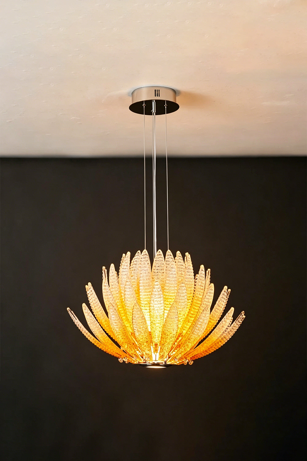 Helios Agave Glass Starburst Chandelier | Glass, Metal | Amber glass variant fully lit against a black background, creating a fiery warm glow | Isolated shot | Samu Lamp
