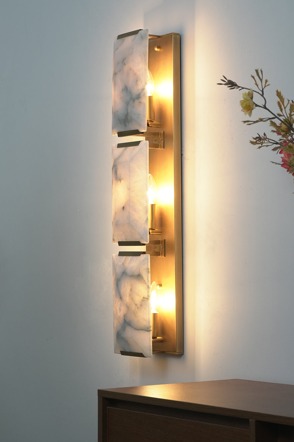 Side view of lit 3-panel alabaster wall lamp | Brass, Alabaster | Showing warm light diffusion against wall | Samu Lamp