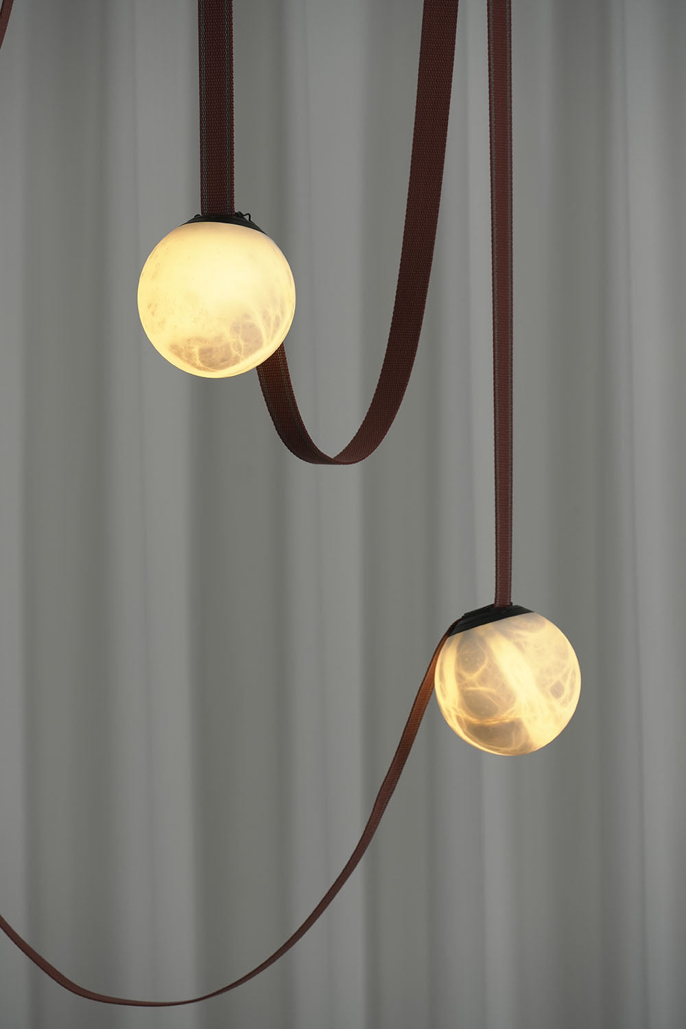 Albiane Draped Chandelier | Alabaster and Woven Rope | Two staggered illuminated globes against dark wall | Samu Lamp