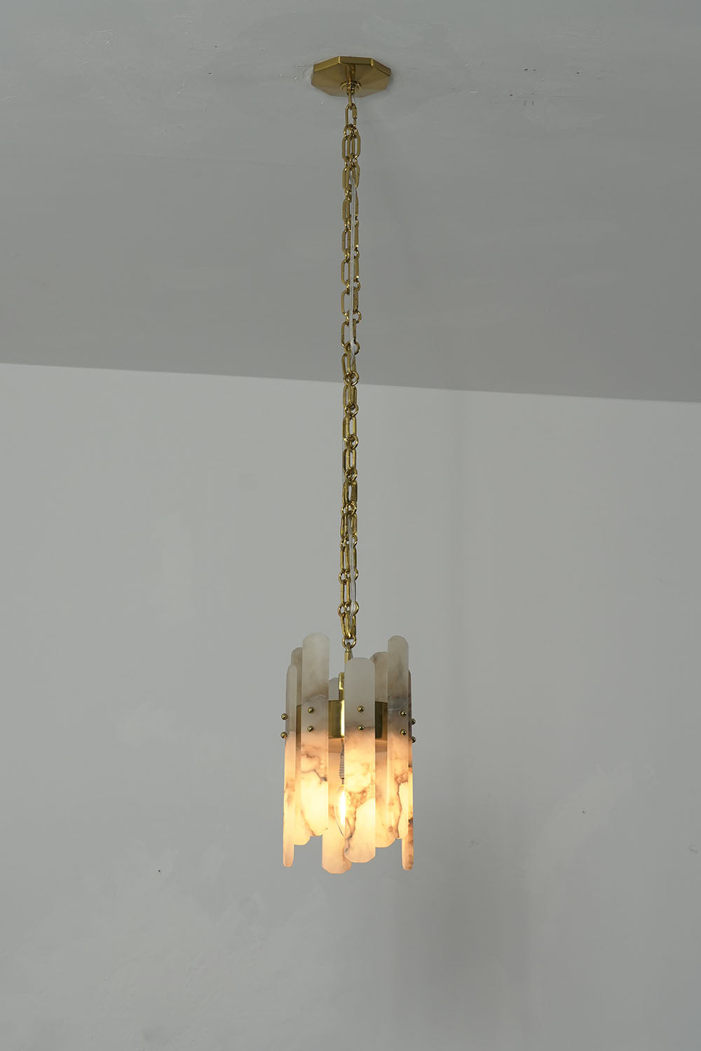 Albrenne Alabaster Mini Pendant | Natural Stone and Brass | Vertical profile illuminated against white wall | Samu Lamp