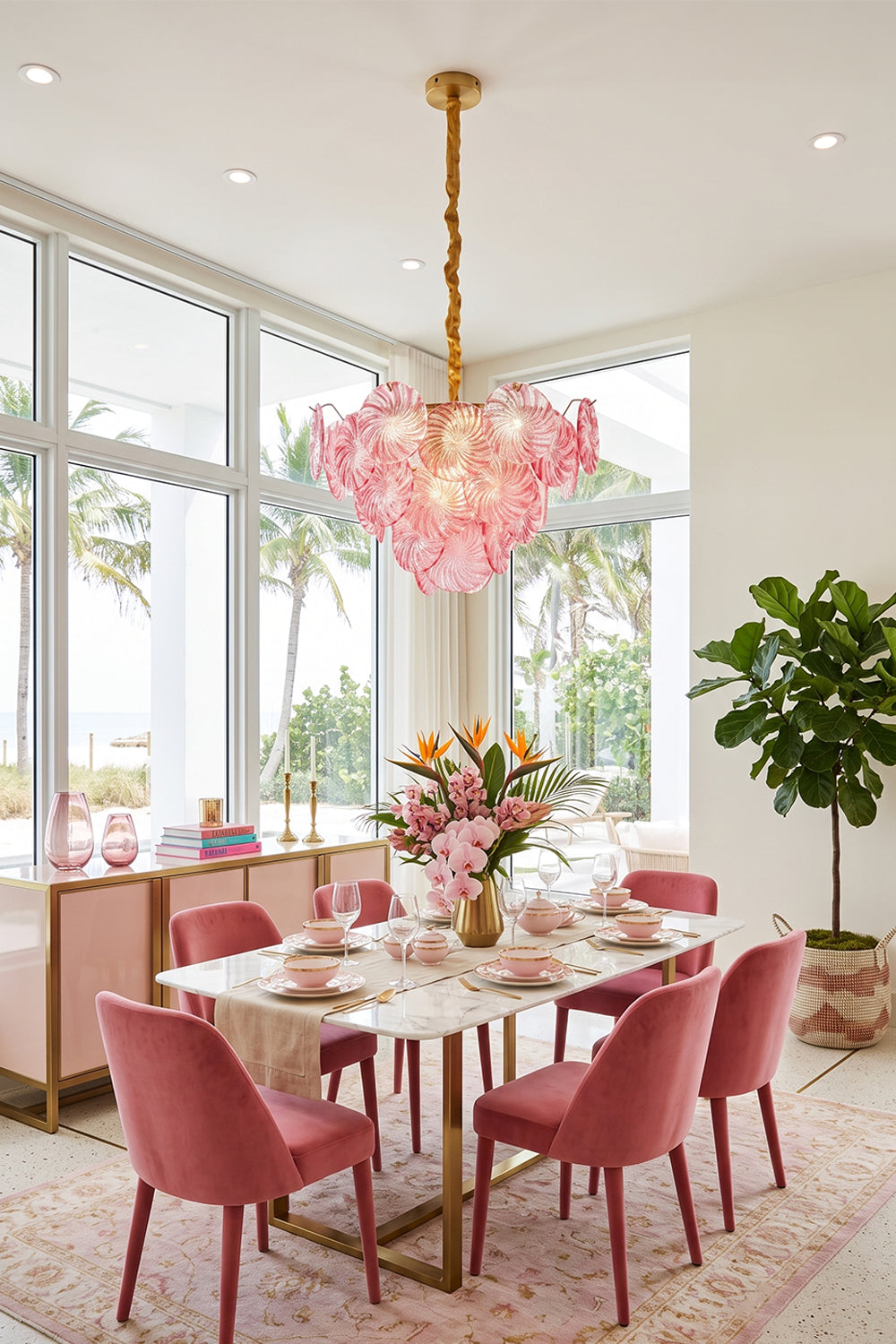Amara Pink Glass Petal Chandelier | Pink Dining Room | The pink glass petal fixture serving as a stunning centerpiece above a dining table surrounded by plush pink velvet chairs | Samu Lamp