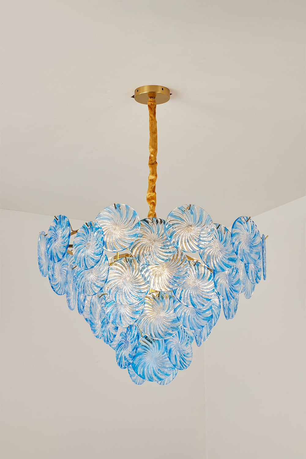 Amara Pink Glass Petal Chandelier | Blue Studio View | Studio presentation of the fully illuminated sea-blue glass petal variation casting a vibrant glow against a plain wall | Samu Lamp