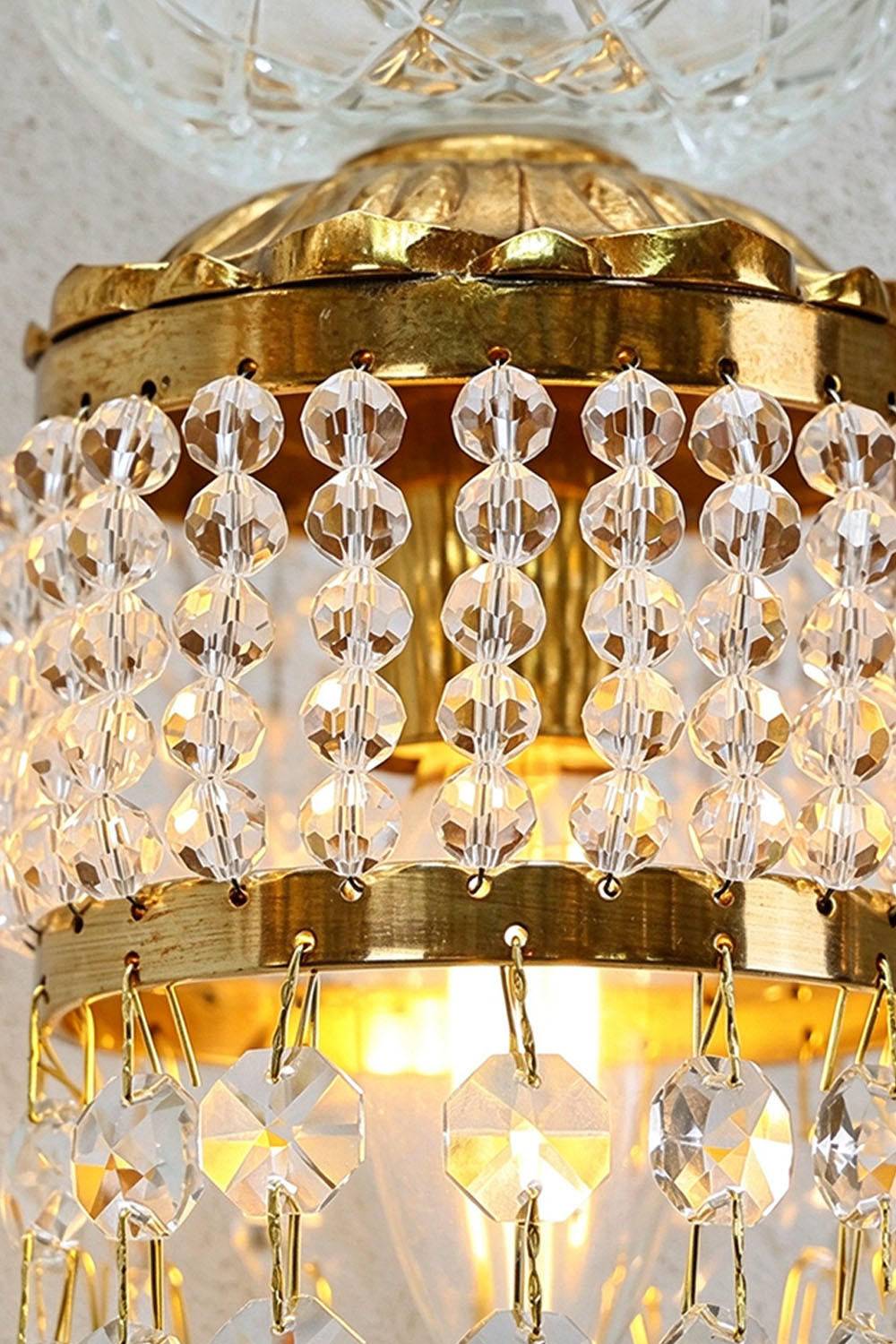 Ambrelise Cherub Wall Sconce | Crystal and Cast Brass | Lit close-up of shimmering crystal beads and gold crown | Samu Lamp