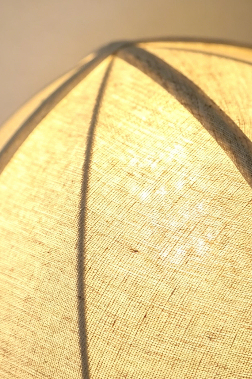 Angolo Canted Faceted Wood Table Lamp | Wood, Fabric, Metal | Macro close-up of the lit fabric lampshade, highlighting the ribbed panels and textured material | Detail shot | Samu Lamp