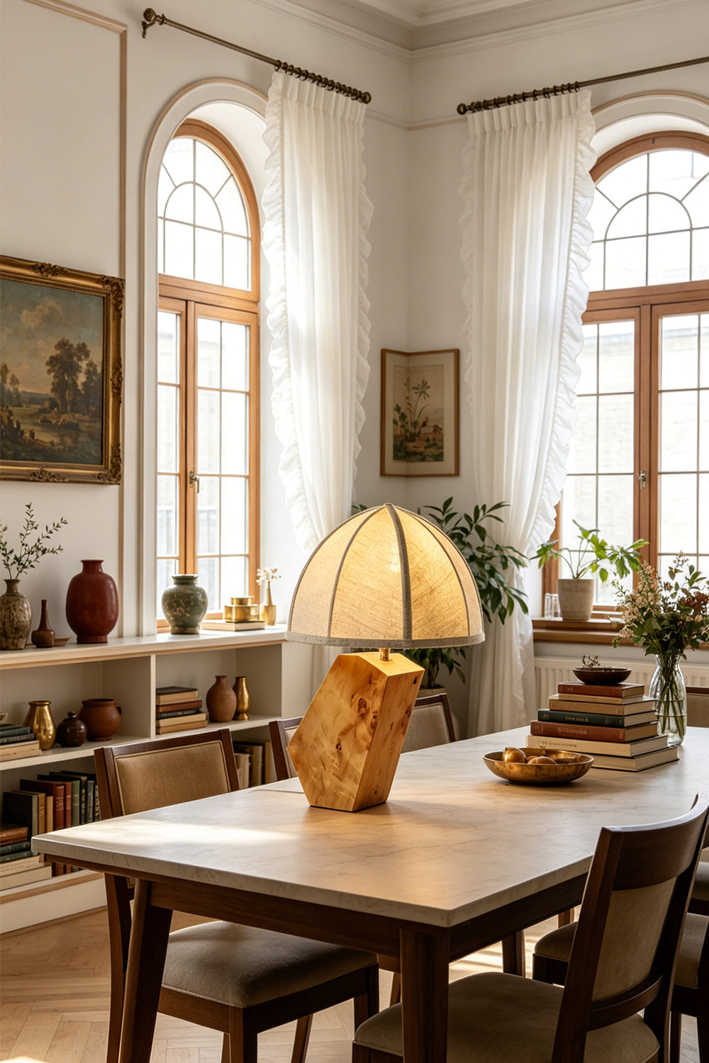 Angolo Canted Faceted Wood Table Lamp | Wood, Fabric, Metal | Placed on a large wooden dining table in a rustic dining room with arched windows and bookshelves | Samu Lamp