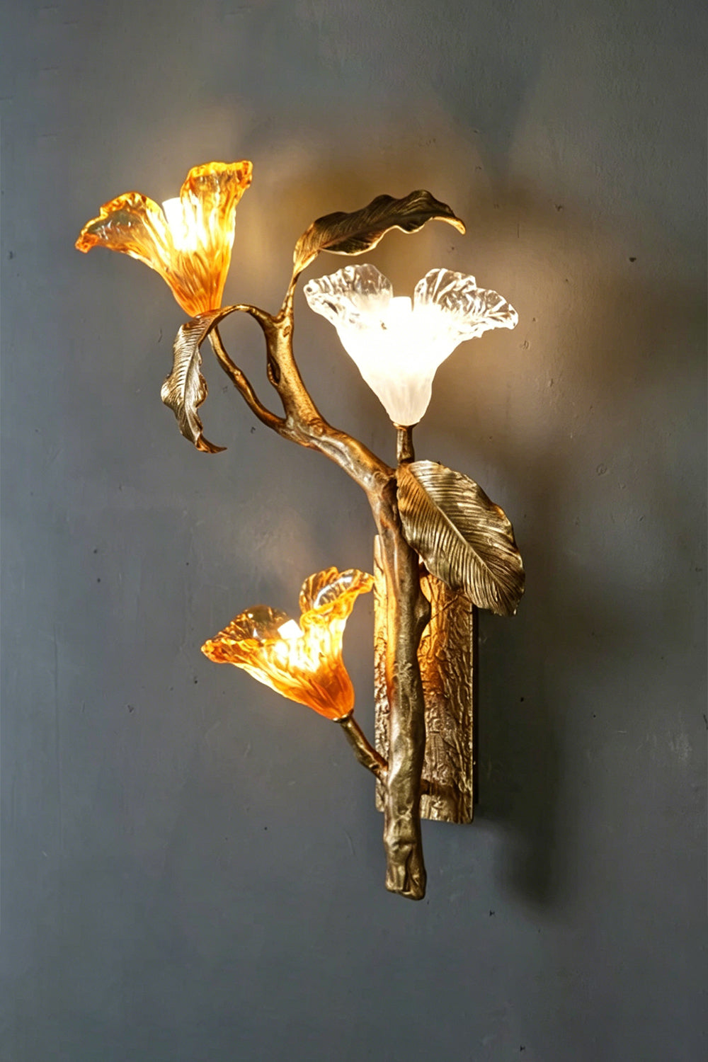 Arboreal Bloom Brass Wall Lamp | Brass, Glass | Frontal view of the fully lit lamp against a grey textured wall | Isolated shot | Samu Lamp