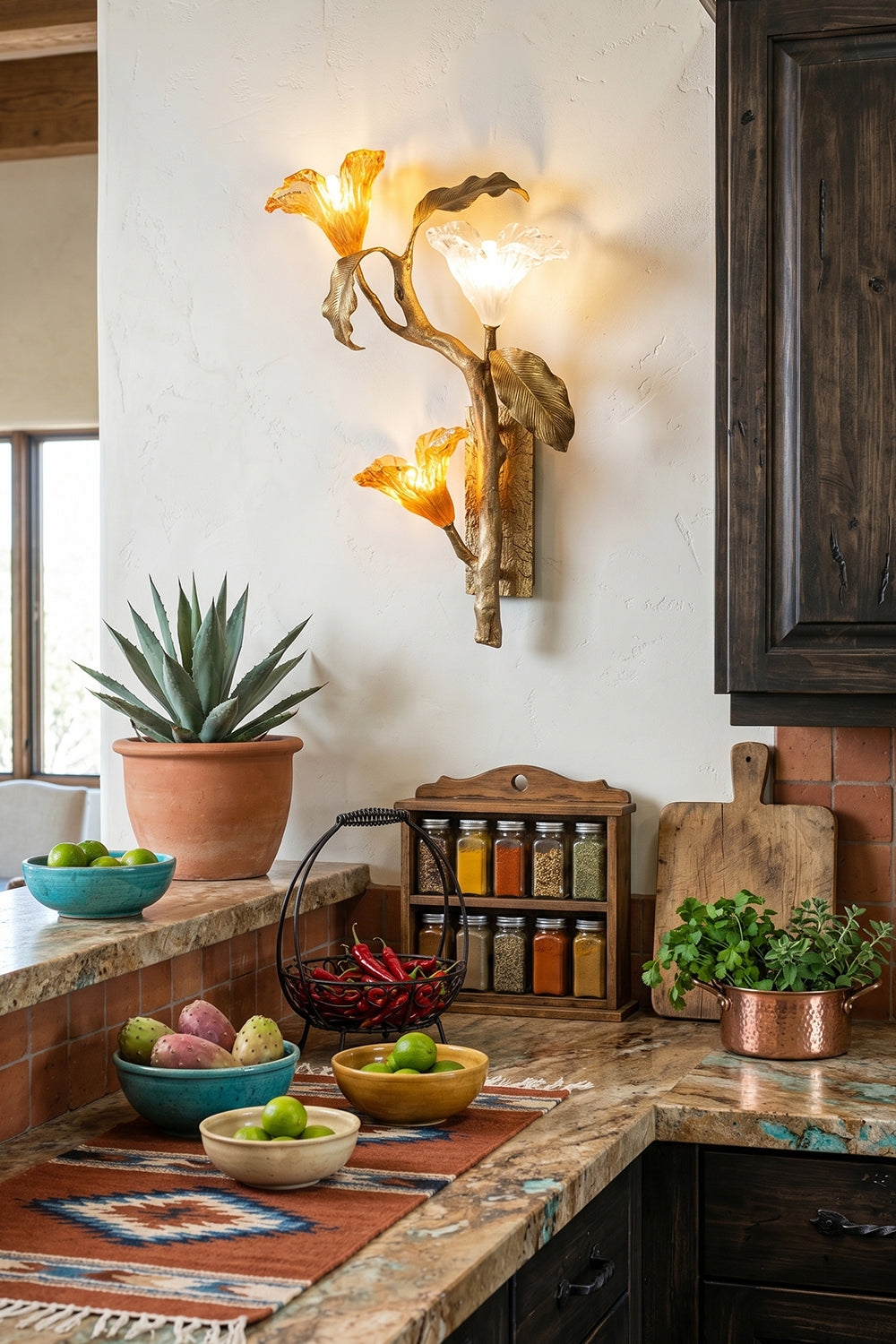 Arboreal Bloom Brass Wall Lamp | Brass, Glass | The Arboreal Bloom brass wall lamp positioned on a textured wall above a rustic fireplace mantel with a distressed mirror, an eclectic orange sofa, and diverse potted plants | Lifestyle in-situ shot | Samu LampArboreal Bloom
