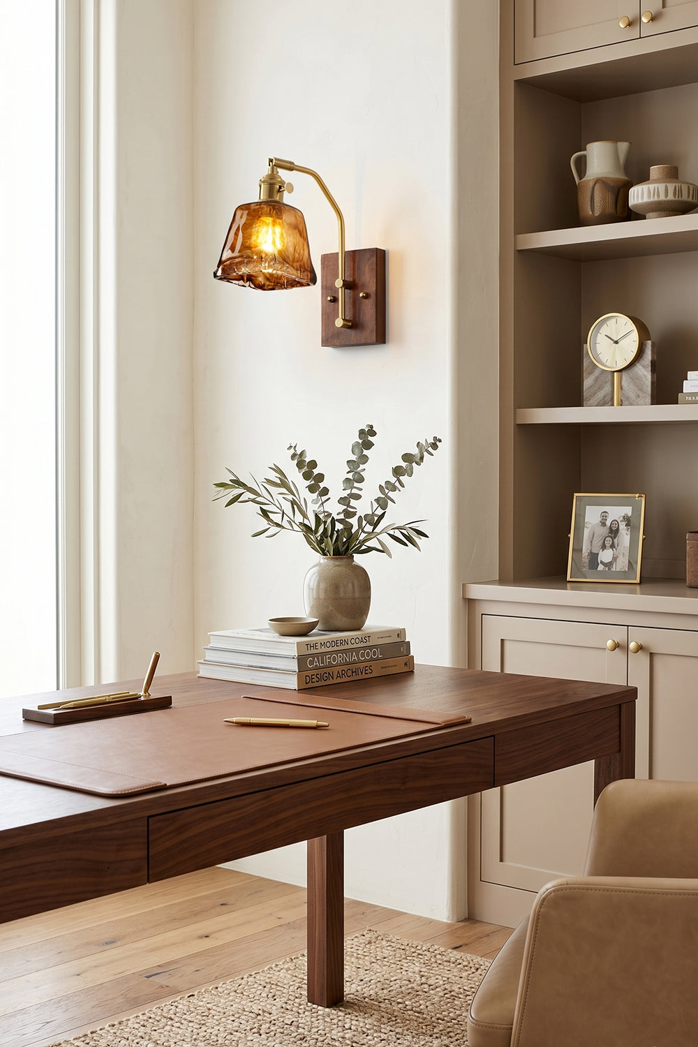 Arlo Amber Ripple Wall Lamp | Glass, Metal, Wood | Providing a warm ambient glow over a dark wood desk workspace in a traditional home library with built-in shelves | Samu Lamp