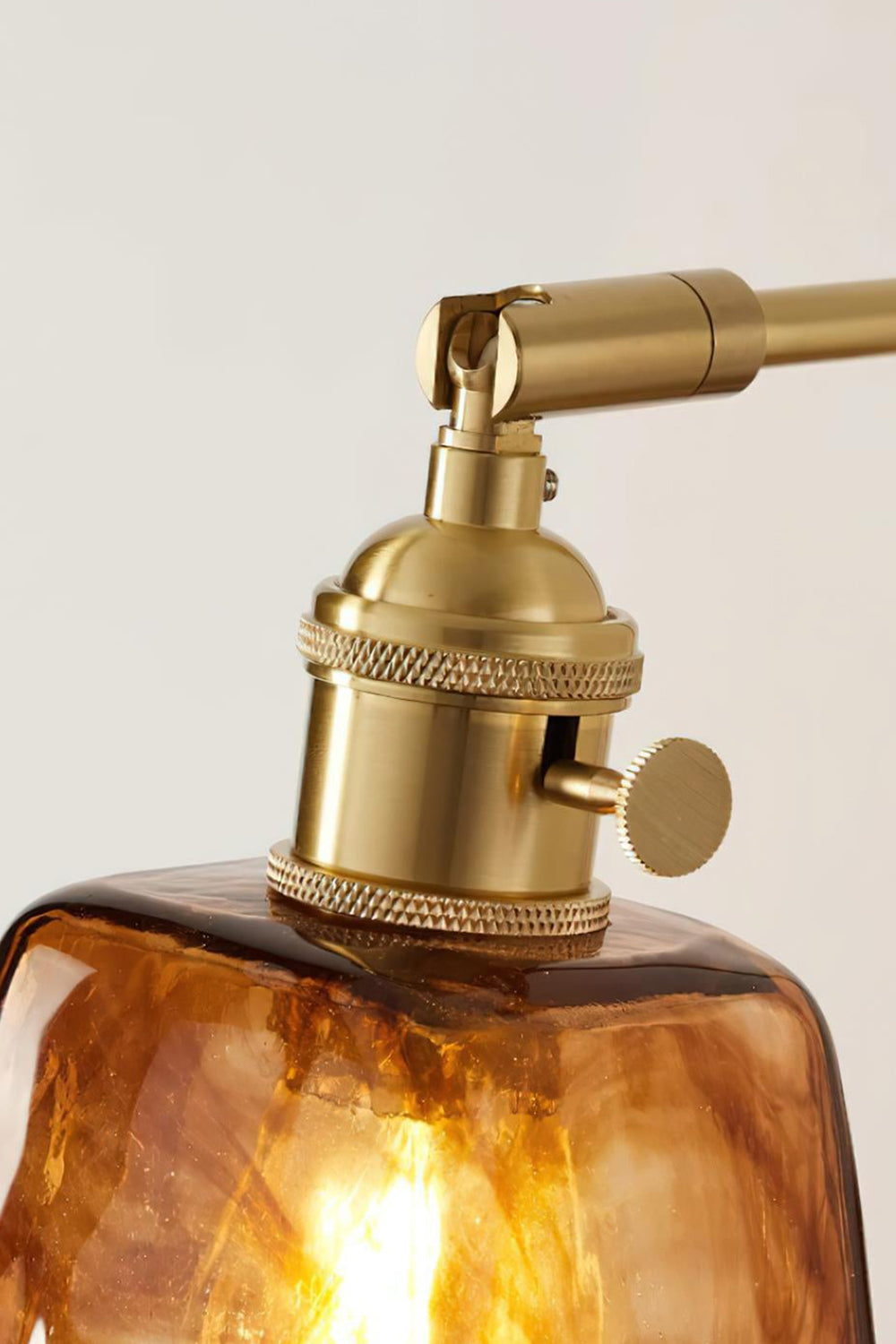 Arlo Amber Ripple Wall Lamp | Glass, Metal, Wood | Close-up focus on the polished gold brass socket cap assembly with a turn-knknob switch above the glass rim | Detail shot | Samu Lamp