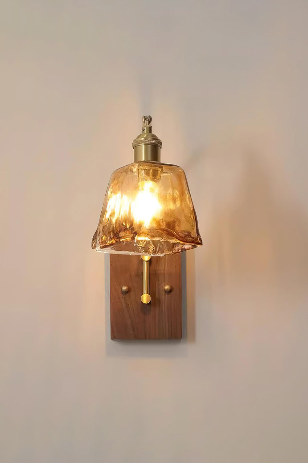 Arlo Amber Ripple Wall Lamp | Glass, Metal, Wood | Front view of the fully illuminated amber glass sconce radiating soft warm light against a neutral grey wall | Samu Lamp