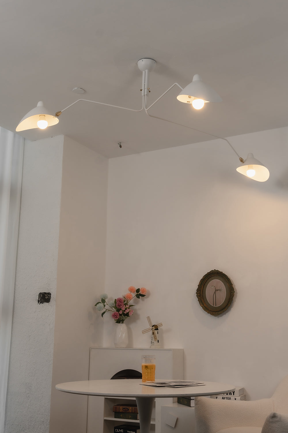 Lit white 3-arm articulated spider light | Metal | Interior mood shot above a round dining table | Samu Lamp