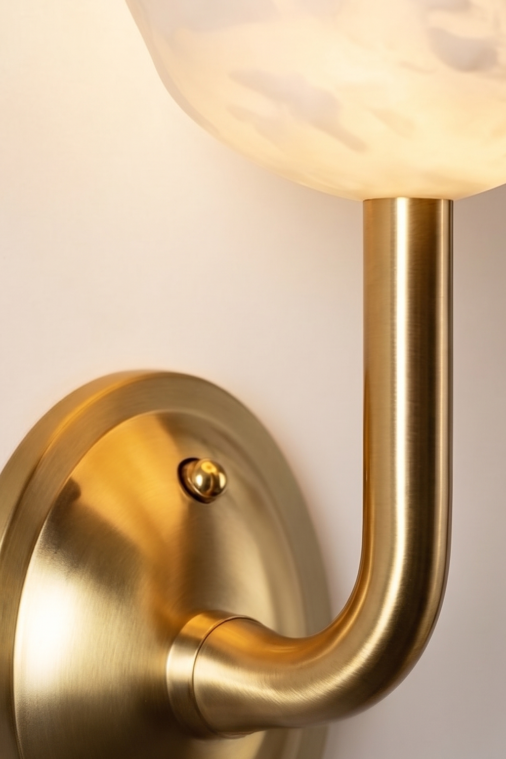 Ascendant Wall Lamp hardware detail | Brass | Close-up of polished brass base and curved arm | Samu Lamp