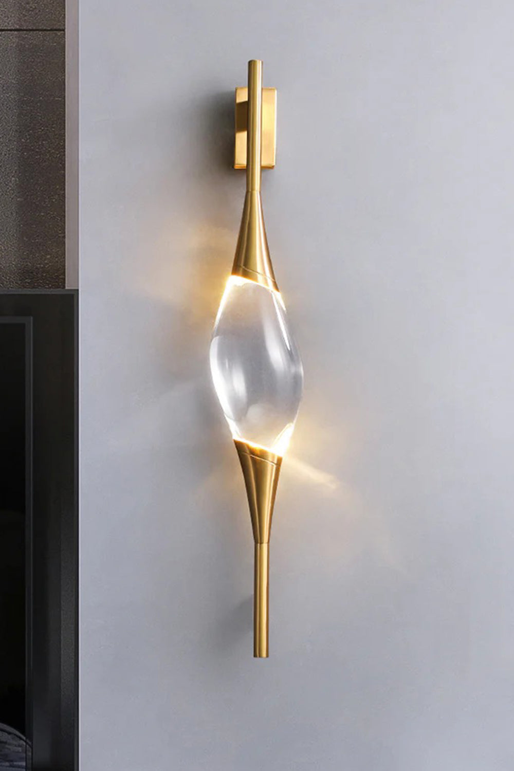 Astraea Crystal Linear Wall Sconce | Crystal, Brass | Studio view of the fully lit linear crystal sconce casting an elegant bow-tie shaped warm light halo on a light grey wall | Samu Lamp