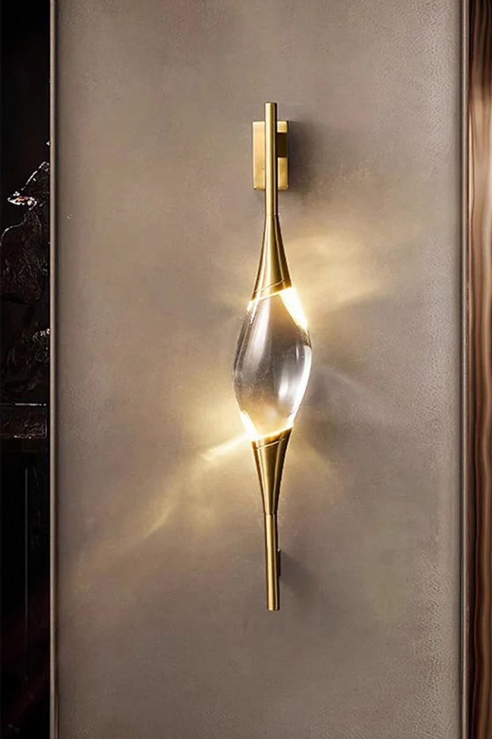 Astraea Crystal Linear Wall Sconce | Crystal, Brass | Staged studio shot of the illuminated golden wall lamp radiating a bright warm glow against a dark brown textured background | Samu Lamp
