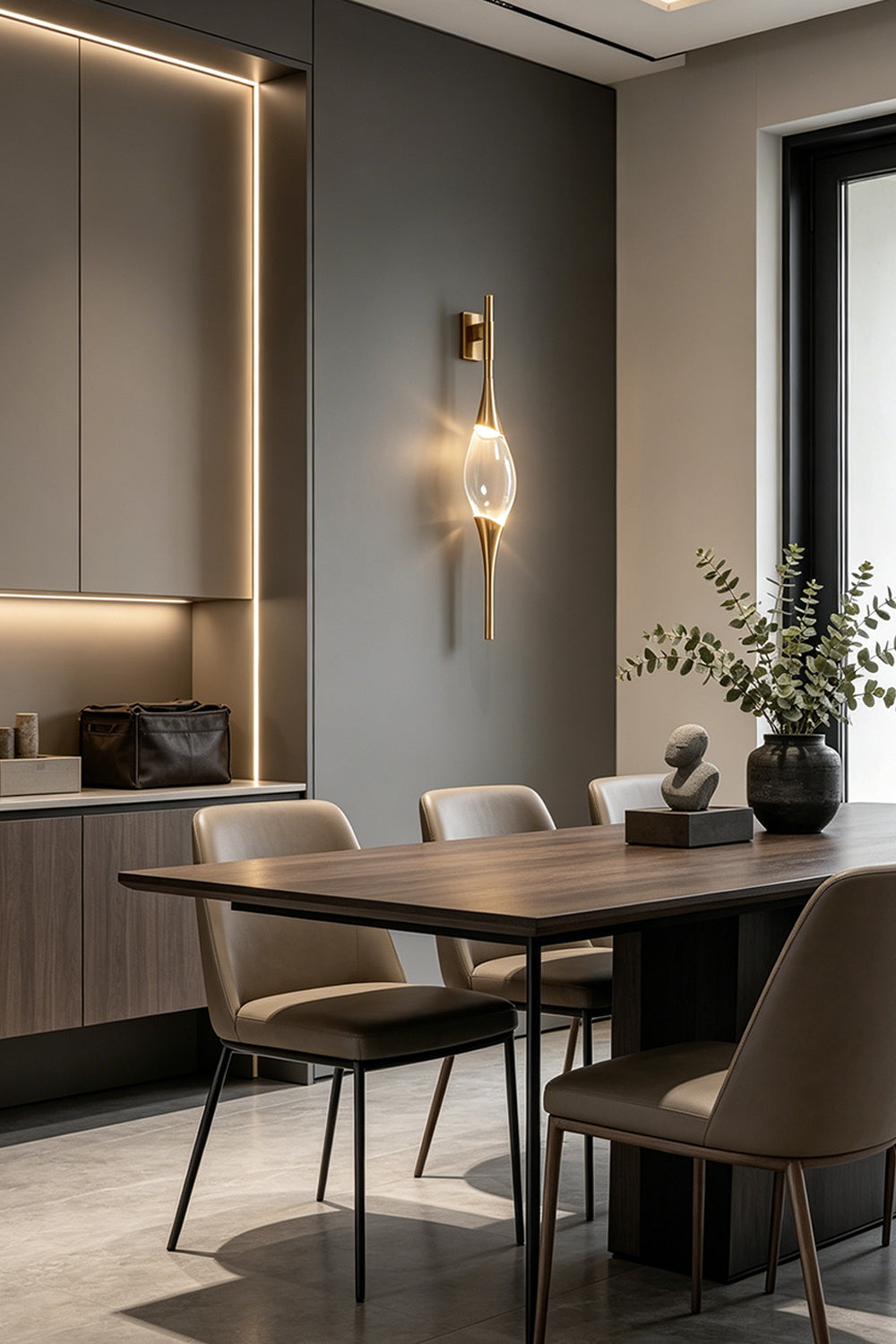 Astraea Crystal Linear Wall Sconce | Crystal, Brass | Providing sophisticated accent lighting on a dark grey wall in a contemporary dining room setup | Samu Lamp