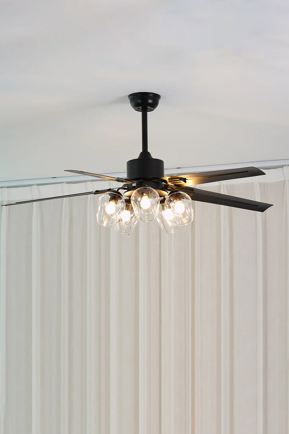 Astraea Modern Glass Globe Ceiling Fan Light | Glass, Metal, Wood | Studio view of the fully illuminated glass globe chandelier fan casting a cozy glow against a clean grey backdrop | Samu Lamp