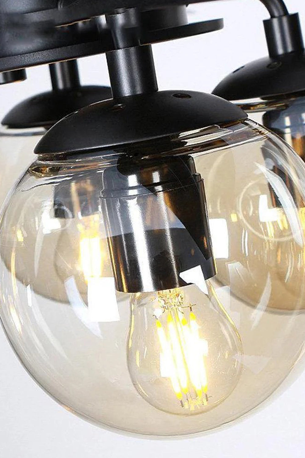 Astraea Modern Glass Globe Ceiling Fan Light | Glass, Metal, Wood | Macro close-up focus on a single illuminated round glass globe shade containing a warm amber Edison-style LED bulb | Detail shot | Samu Lamp
