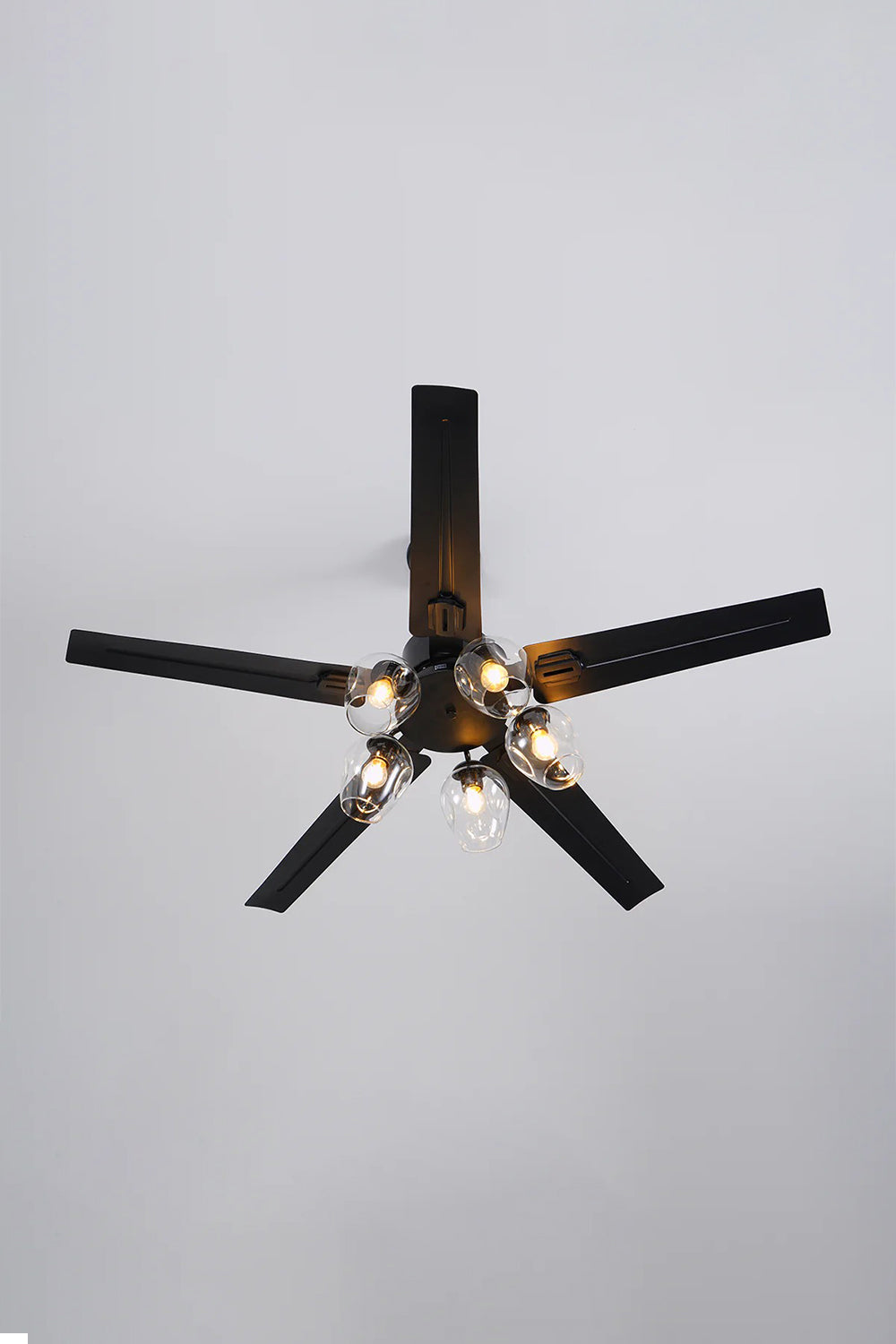 Astraea Modern Glass Globe Ceiling Fan Light | Glass, Metal, Wood | Direct bottom-up perspective showing the symmetrical star pattern of the five dark blades surrounding the five-light globe cluster | Detail shot | Samu Lamp