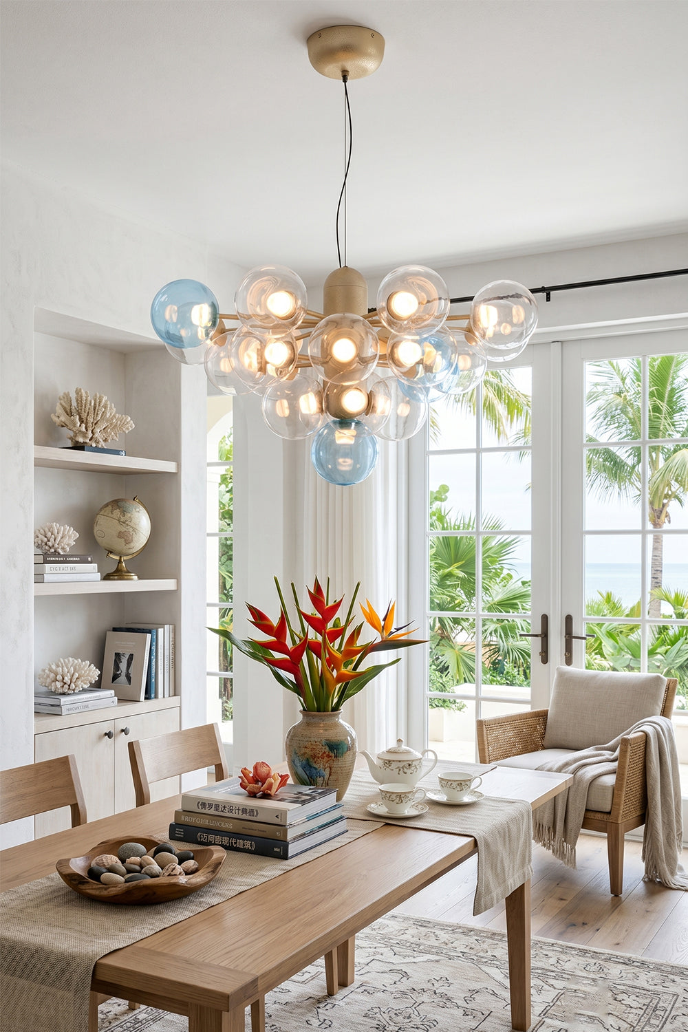 Astraea Prismatic Globe Chandelier | Glass, Metal | Illuminating a bright tropical-style dining room over a wooden table set near large sliding glass doors opening to a garden | Samu Lamp