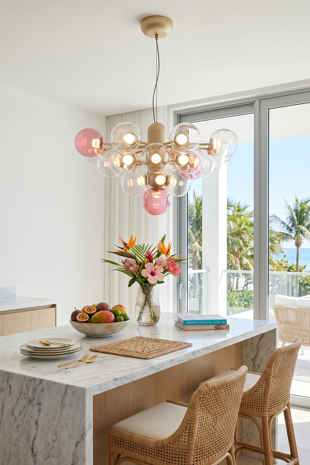 Astraea Prismatic Globe Chandelier | Glass, Metal | Suspended as a playful elegant centerpiece above a pristine white kitchen island counter with woven rattan bar stools in a coastal home | Samu Lamp