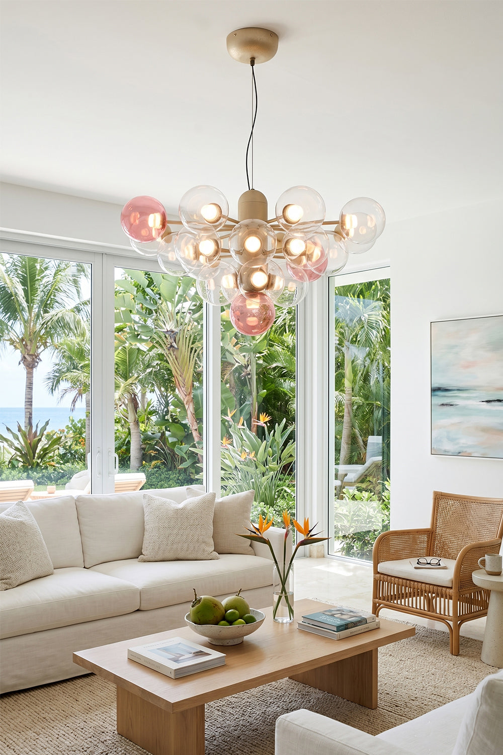 Astraea Prismatic Globe Chandelier | Glass, Metal | Casting a warm ambient glow over a cream fabric sofa and low wood coffee table in a sunlit living room with palm tree views | Samu Lamp