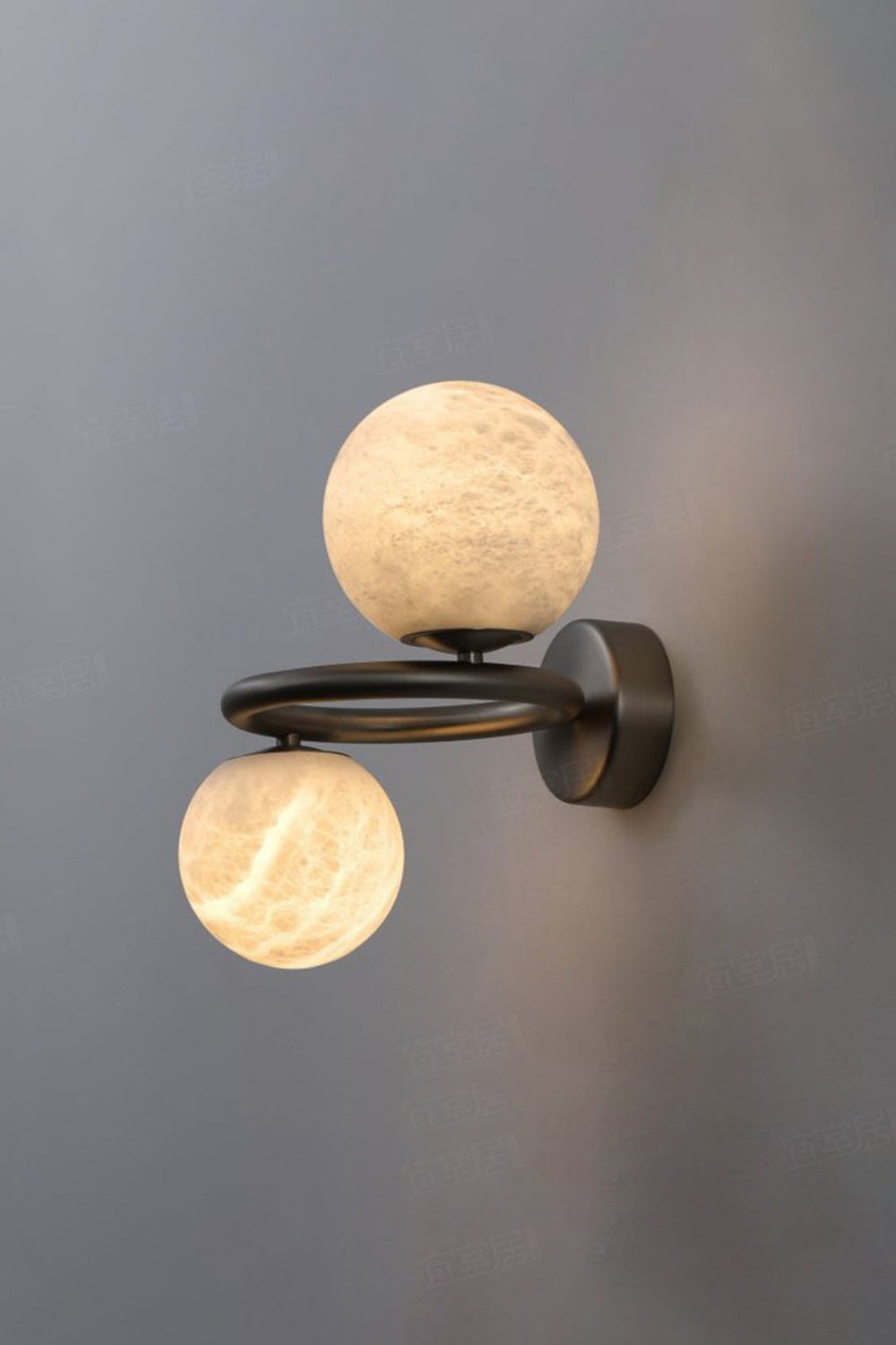Aura Two-Globe Alabaster Wall Sconce showcasing translucent globes and curved metal arm, emitting soft light.