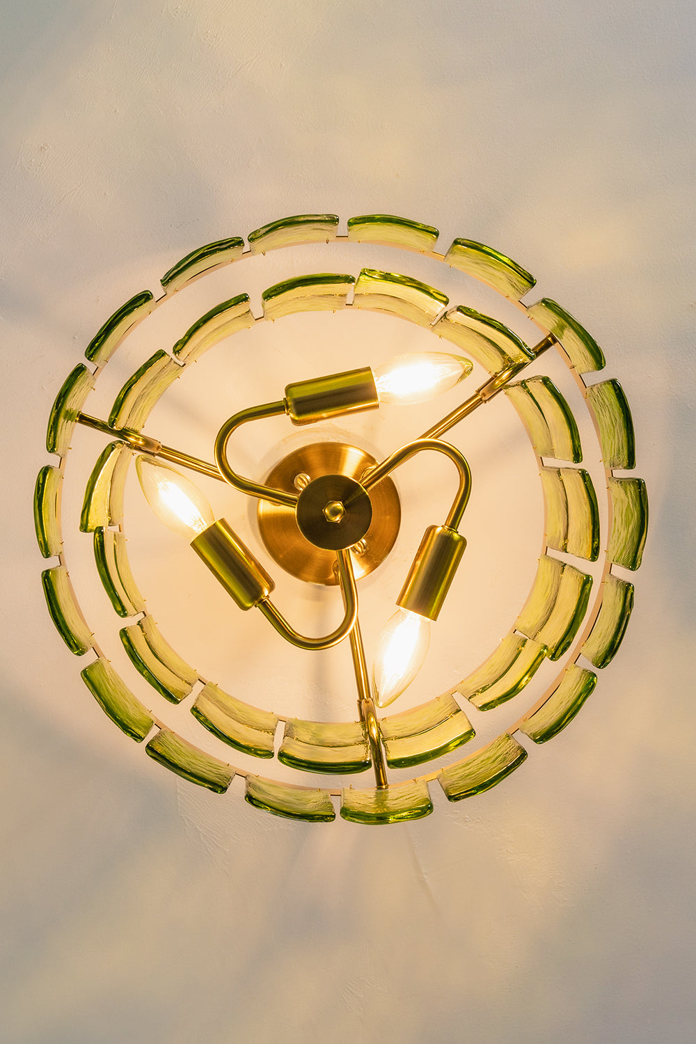 Aura Verdant Tiered Green Glass Ceiling Light | Metal, Glass | Looking directly up at the illuminated ceiling light, showing the symmetrical three-bulb structure | Detail shot | Samu Lamp