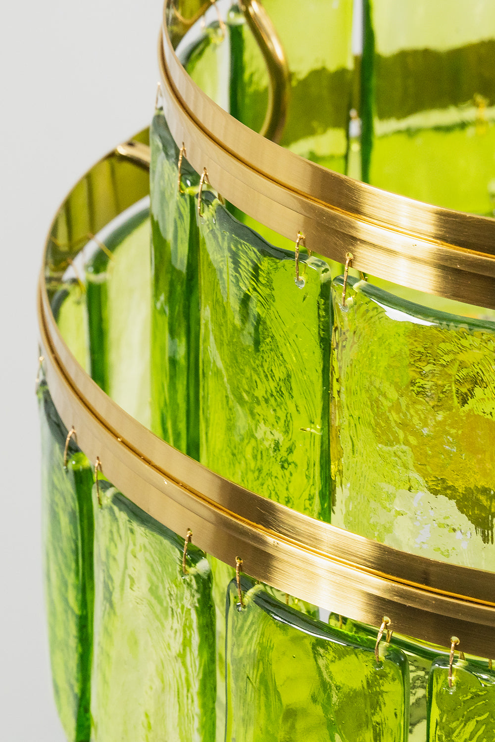 Aura Verdant Tiered Green Glass Ceiling Light | Metal, Glass | Close-up side profile of the brushed gold metal bands and the hooked green glass plates | Detail shot | Samu Lamp