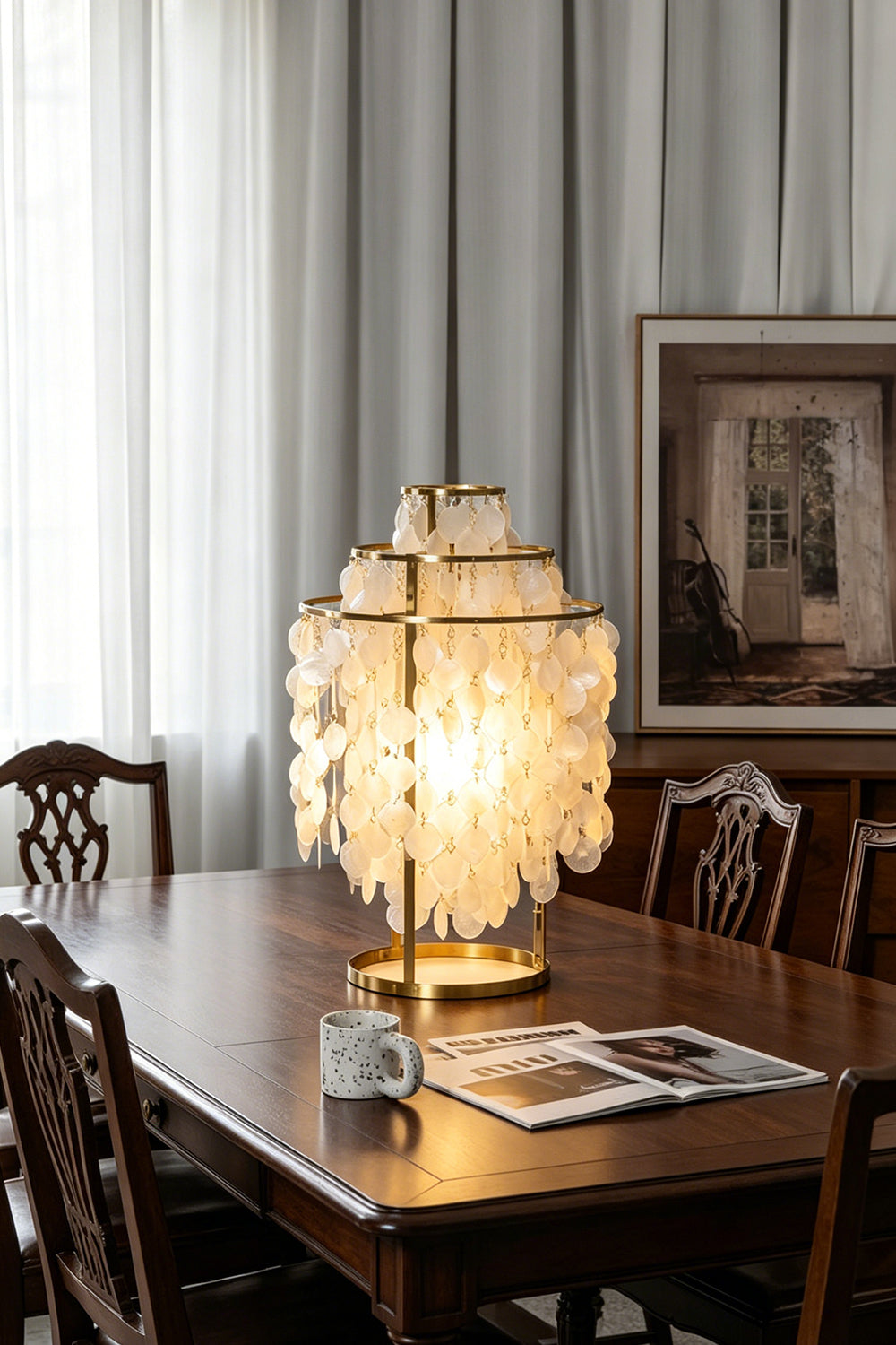 Aurelia Tiered Capiz Table Lamp | Capiz Shell, Metal | Providing a warm golden glow on a long dark wood dining table in a classic traditional dining room | Samu Lamp