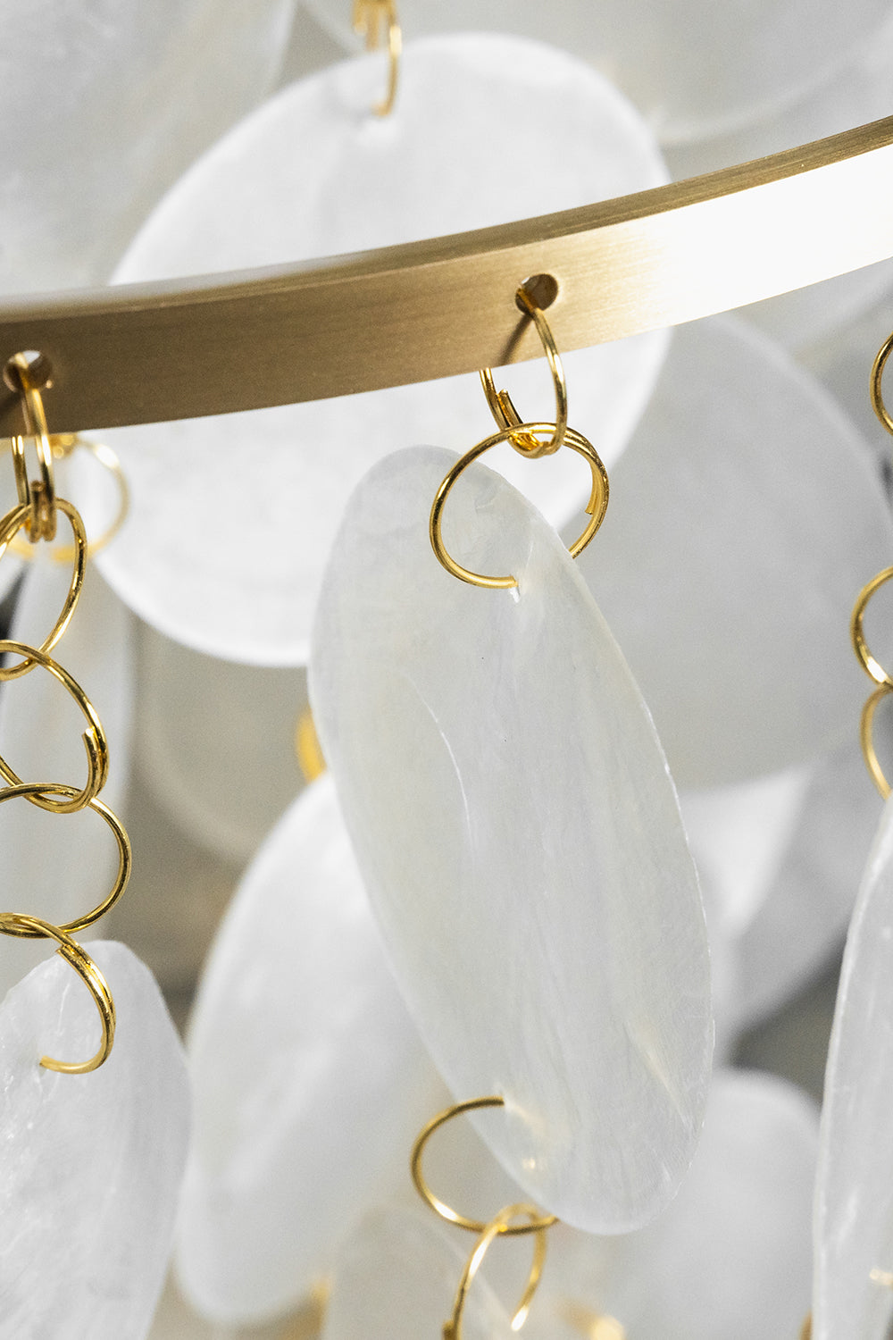 Aurelia Tiered Capiz Table Lamp | Capiz Shell, Metal | Detailed close-up showing the translucent capiz shell discs hanging from gold metal loops on the circular frame | Detail shot | Samu Lamp