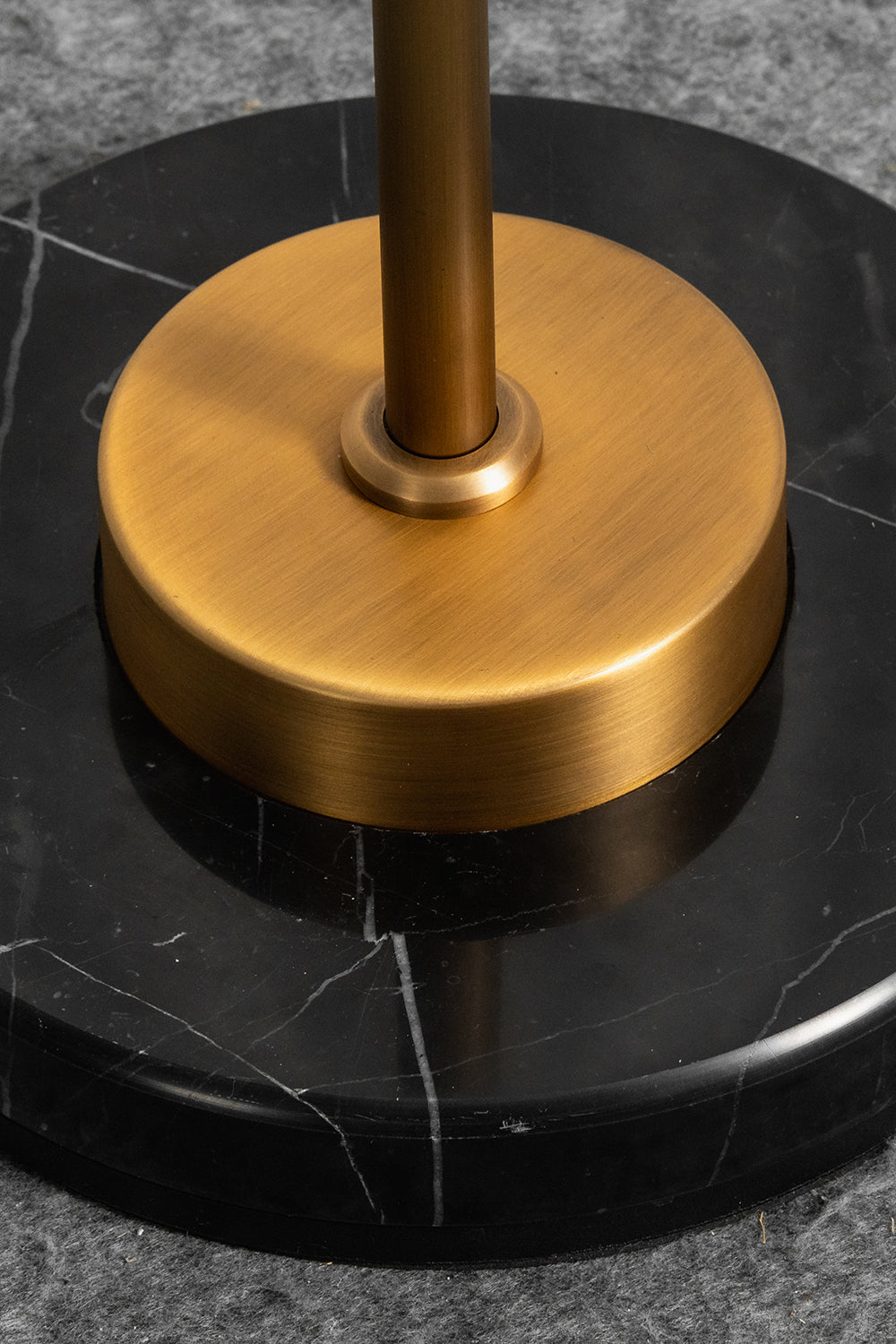 Aurelius Alabaster Brass Floor Lamp | Alabaster, Brass | Close-up structural view of the heavy circular brushed brass stem collar resting on the polished round black marble base plate with white veins | Detail shot | Samu Lamp