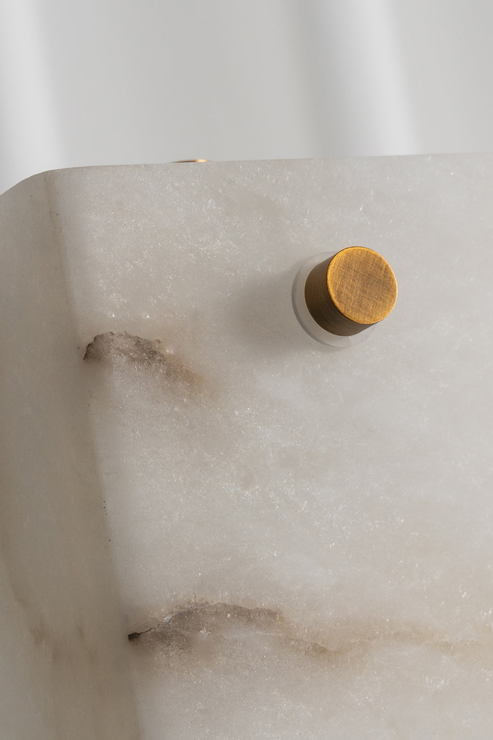 Aurelius Alabaster Brass Floor Lamp | Alabaster, Brass | Macro shot focusing on the external brushed gold brass screw bolt secured onto the natural white alabaster slab displaying rich brown veining | Detail shot | Samu Lamp