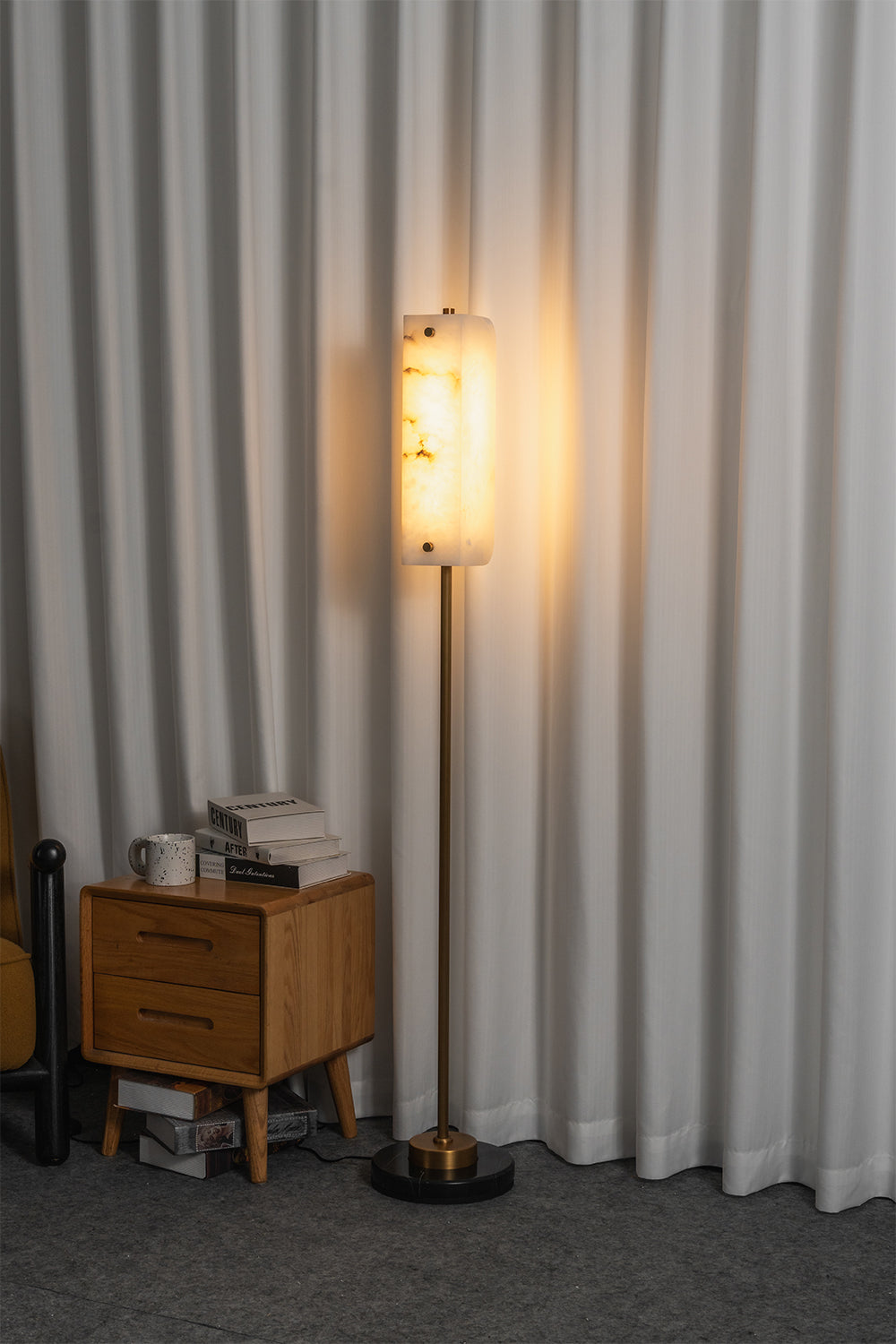 Aurelius Alabaster Brass Floor Lamp | Alabaster, Brass | Fully illuminated linear floor lamp casting a cozy golden ambient glow through the natural stone shade next to a wood side table | Samu Lamp