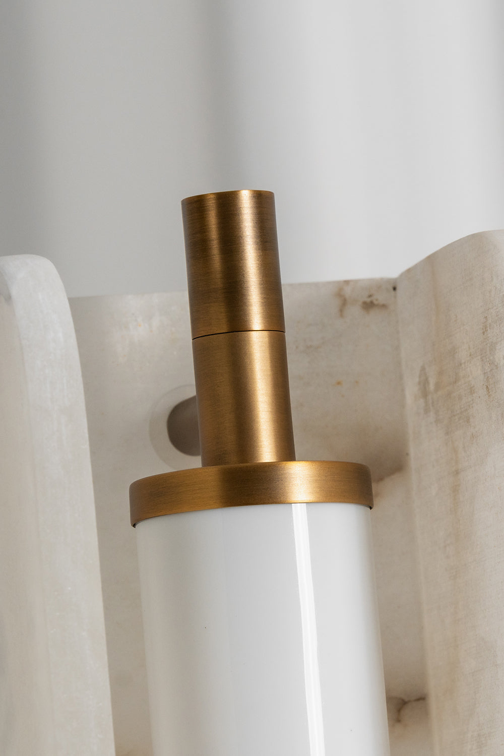 Aurelius Alabaster Brass Floor Lamp | Alabaster, Brass | Close-up focus on the internal gold brass metal bracket holding the frosted tube shade within the natural white alabaster stone | Detail shot | Samu Lamp