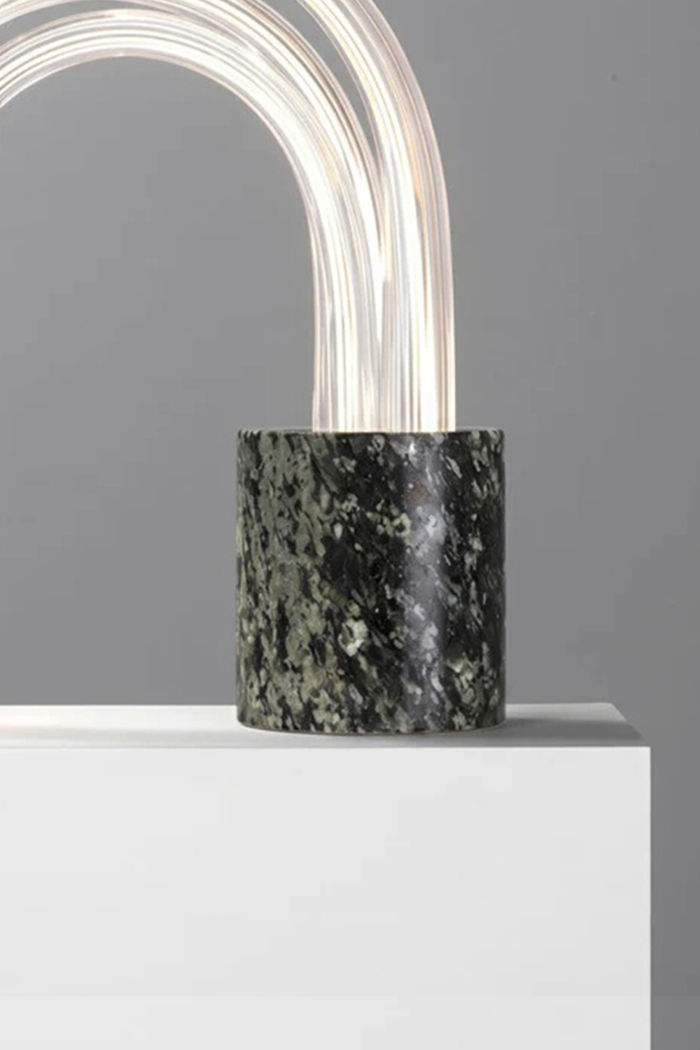 Aurelius Ribbed Marble Table Lamp showcasing a dark marble base with light arcs illuminating from the top.