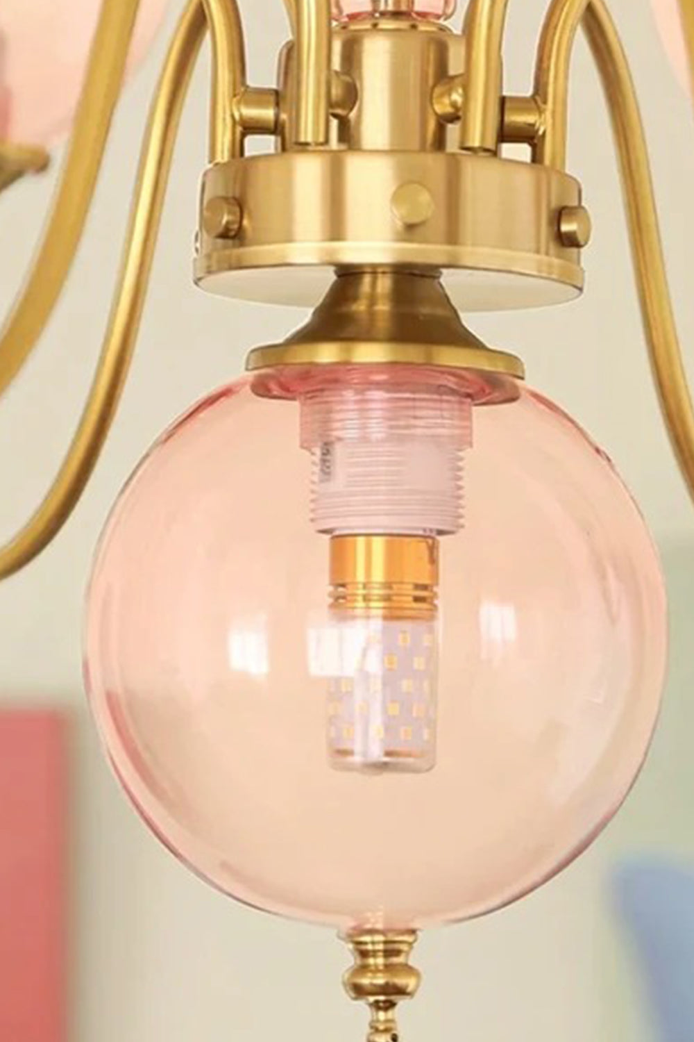 Aveline Globe Cluster Chandelier | Colored Glass and Brass | Close-up view of a single pink glass globe shade with brass fitting | Samu Lamp