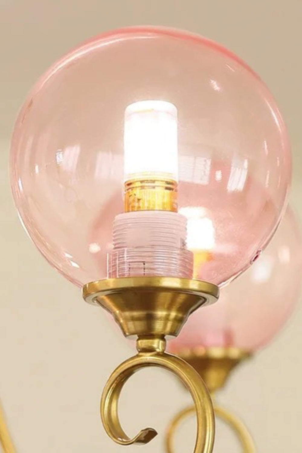 Aveline Globe Cluster Chandelier | Colored Glass and Brass | Macro detail shot of an illuminated pink glass sphere on a brass stem | Samu Lamp