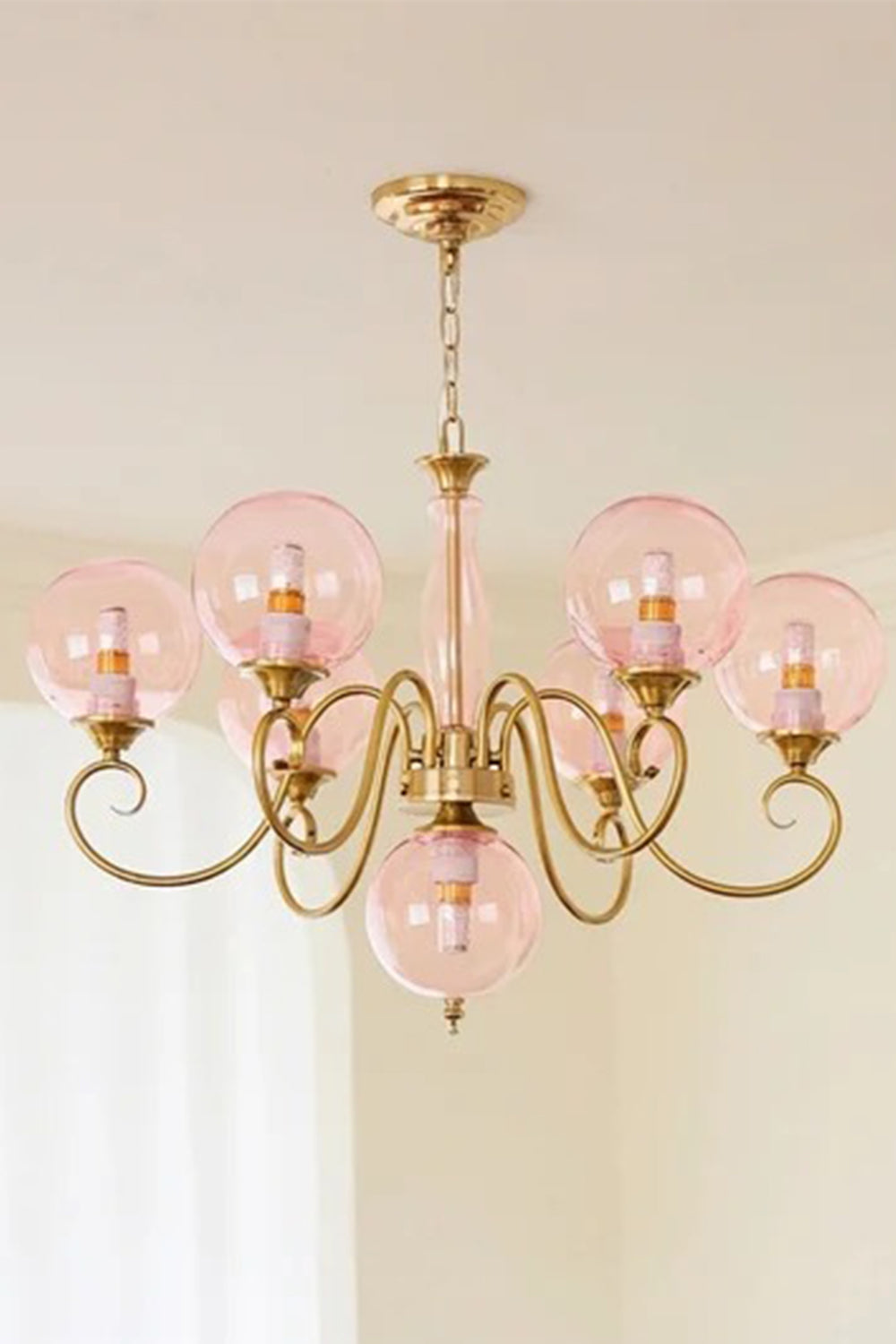 Aveline Globe Cluster Chandelier | Colored Glass and Brass | Front illuminated view displaying pink glass globes against a soft wall | Samu Lamp