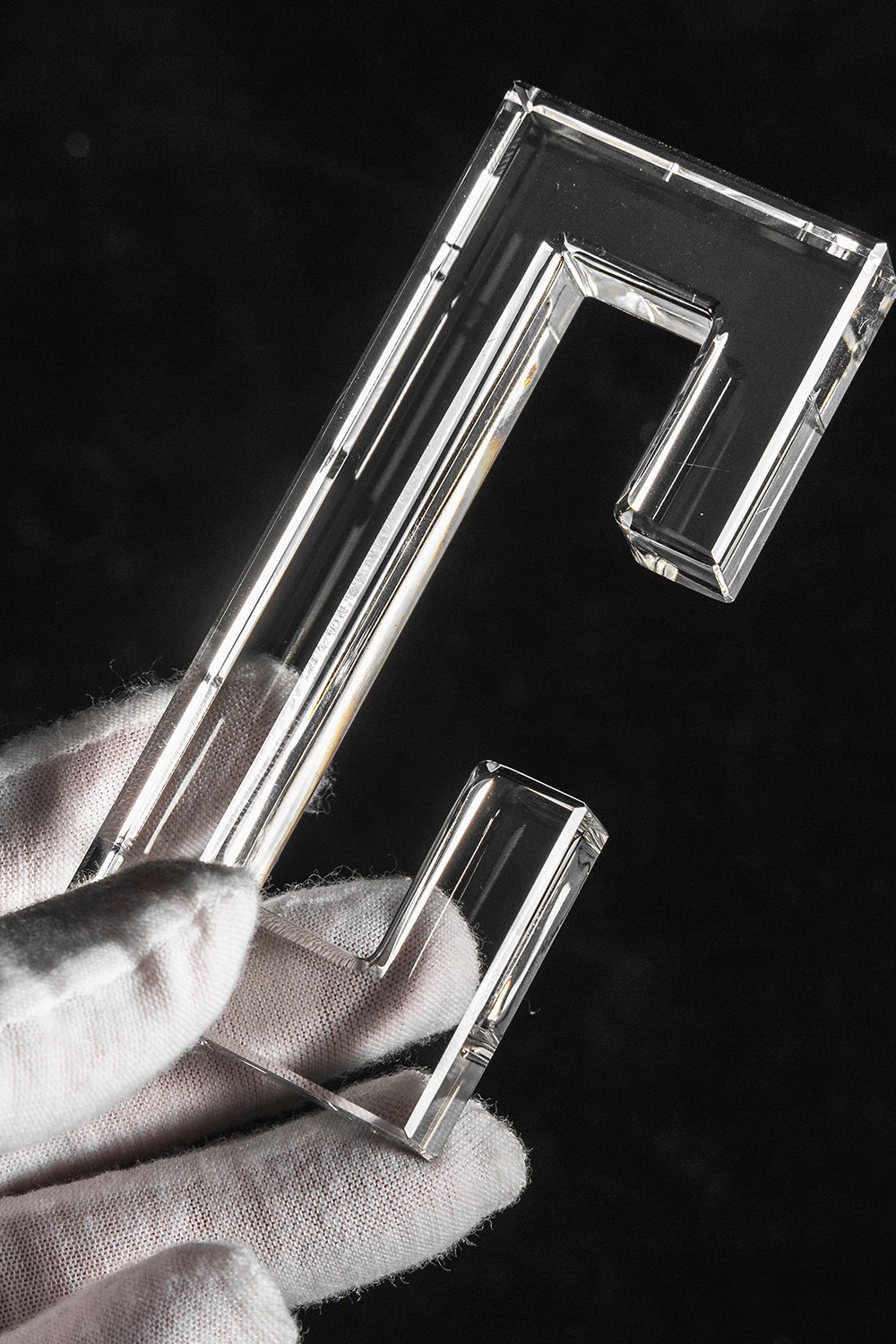 Aven Tiered Glass Prism Chandelier | Glass, Metal | A gloved hand holding a single clear molded rectangular glass link prism hook to showcase size and texture | Detail shot | Samu Lamp