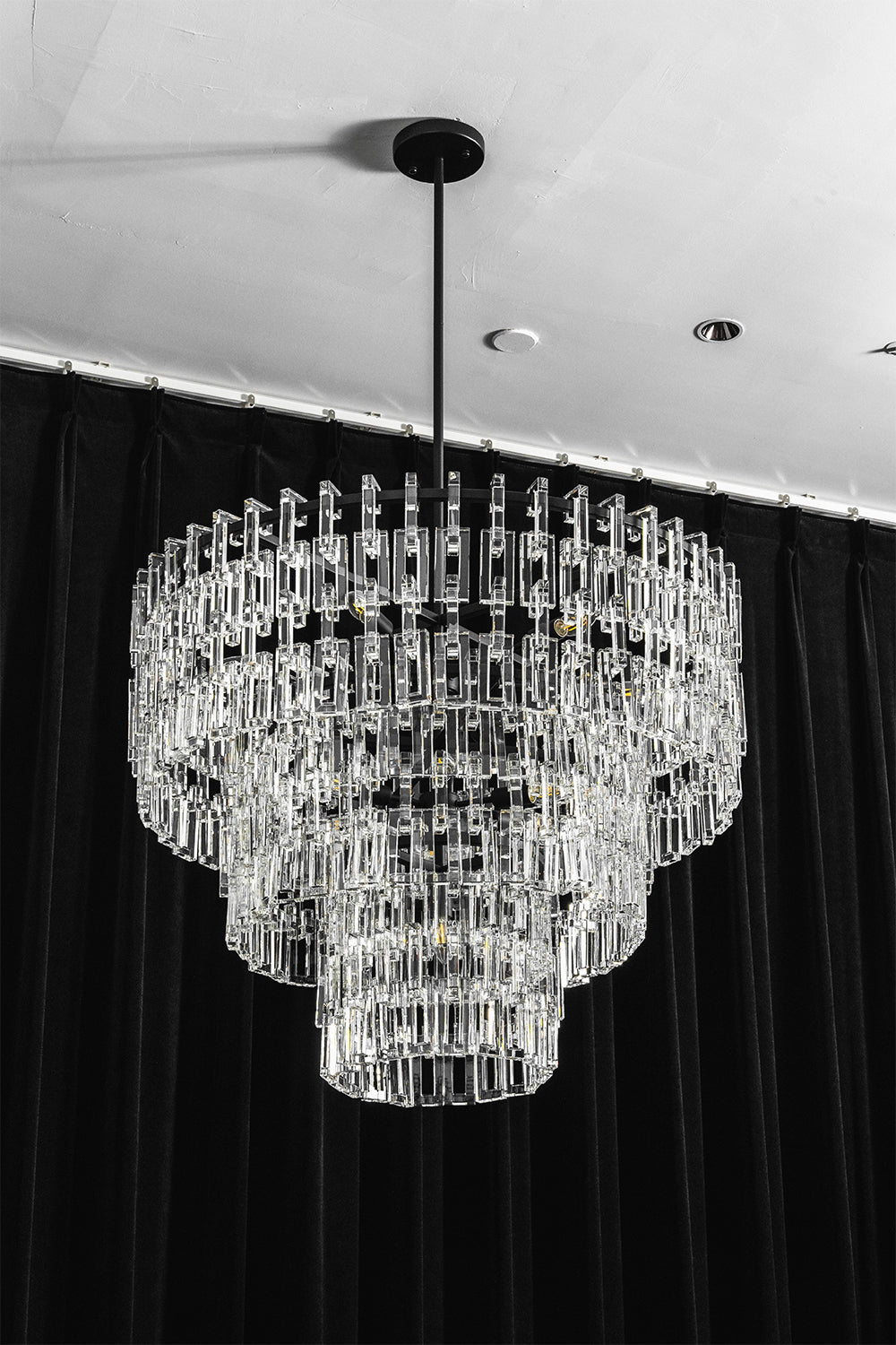 Aven Tiered Glass Prism Chandelier | Glass, Metal | Frontal centered shot of the unlit black metal and clear glass link chandelier variant on a dark studio background | Samu Lamp