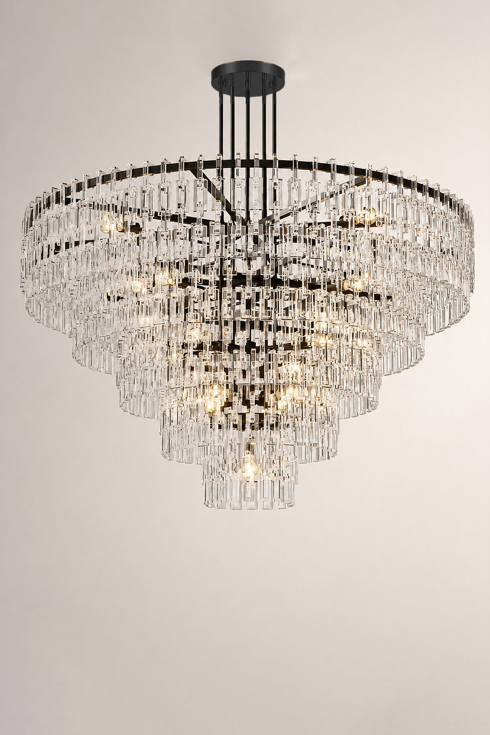 Aven Tiered Glass Prism Chandelier | Glass, Metal | Minimalist mockup shot of the unlit black metal and clear glass tiered chandelier centered against a grey wall | Samu Lamp