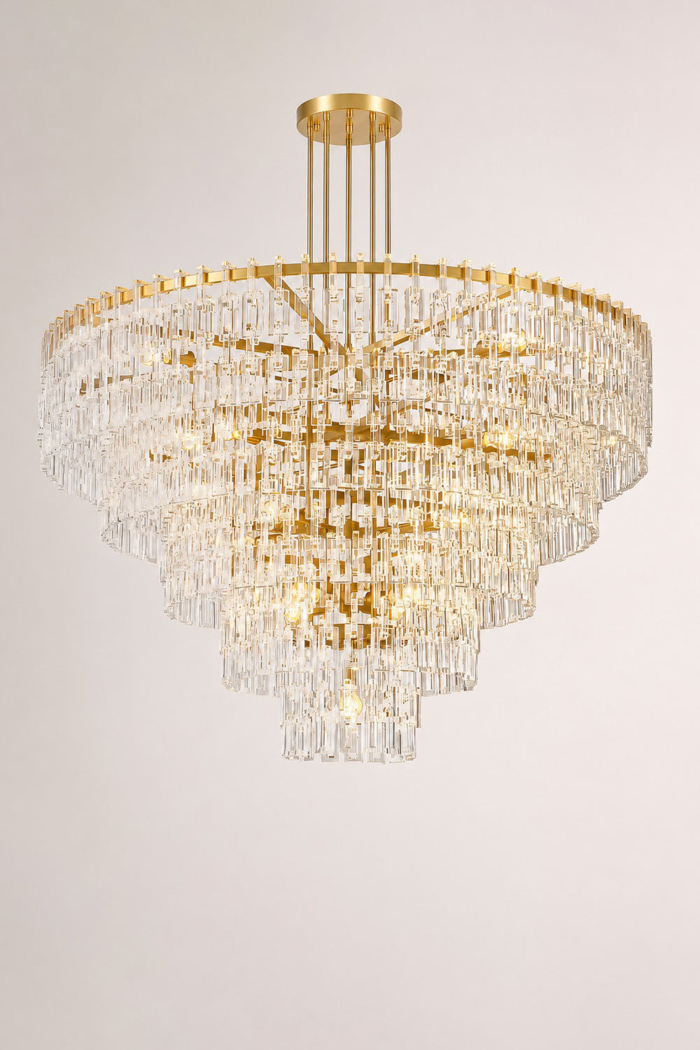 Aven Tiered Glass Prism Chandelier | Glass, Metal | Studio mockup shot of the fully lit gold brass tiered crystal chandelier radiating a rich ambient glow on a grey background | Samu Lamp