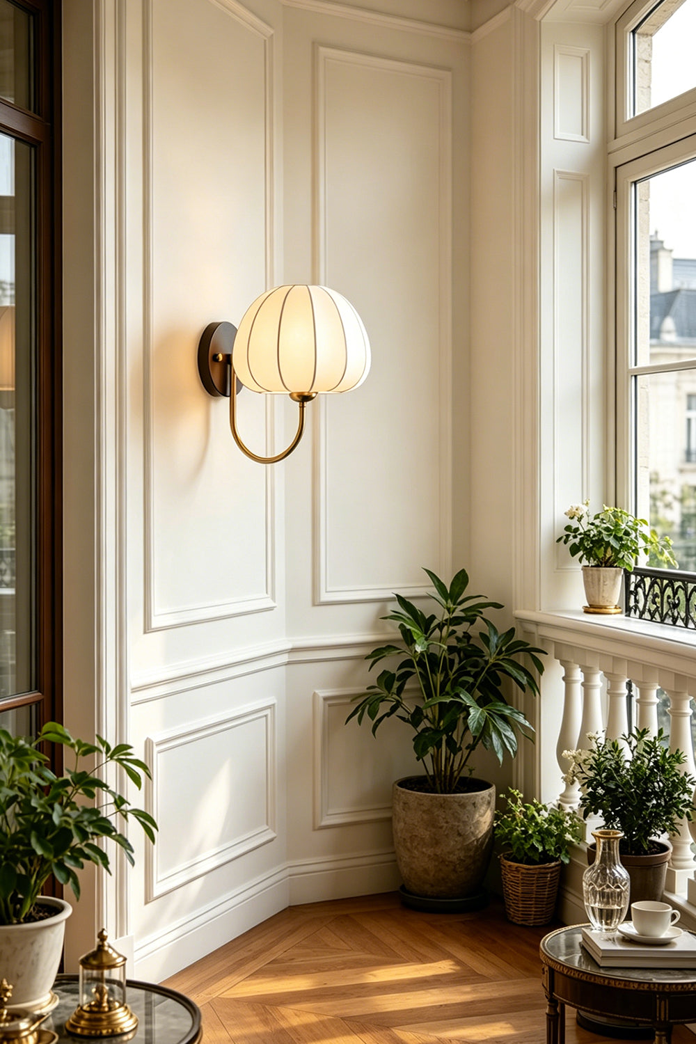 Baird Mid Century Pumpkin Wall Lamp | Metal, Fabric, Wood | Illuminating a bright, sunlit room corner filled with green potted plants near a window | Samu Lamp
