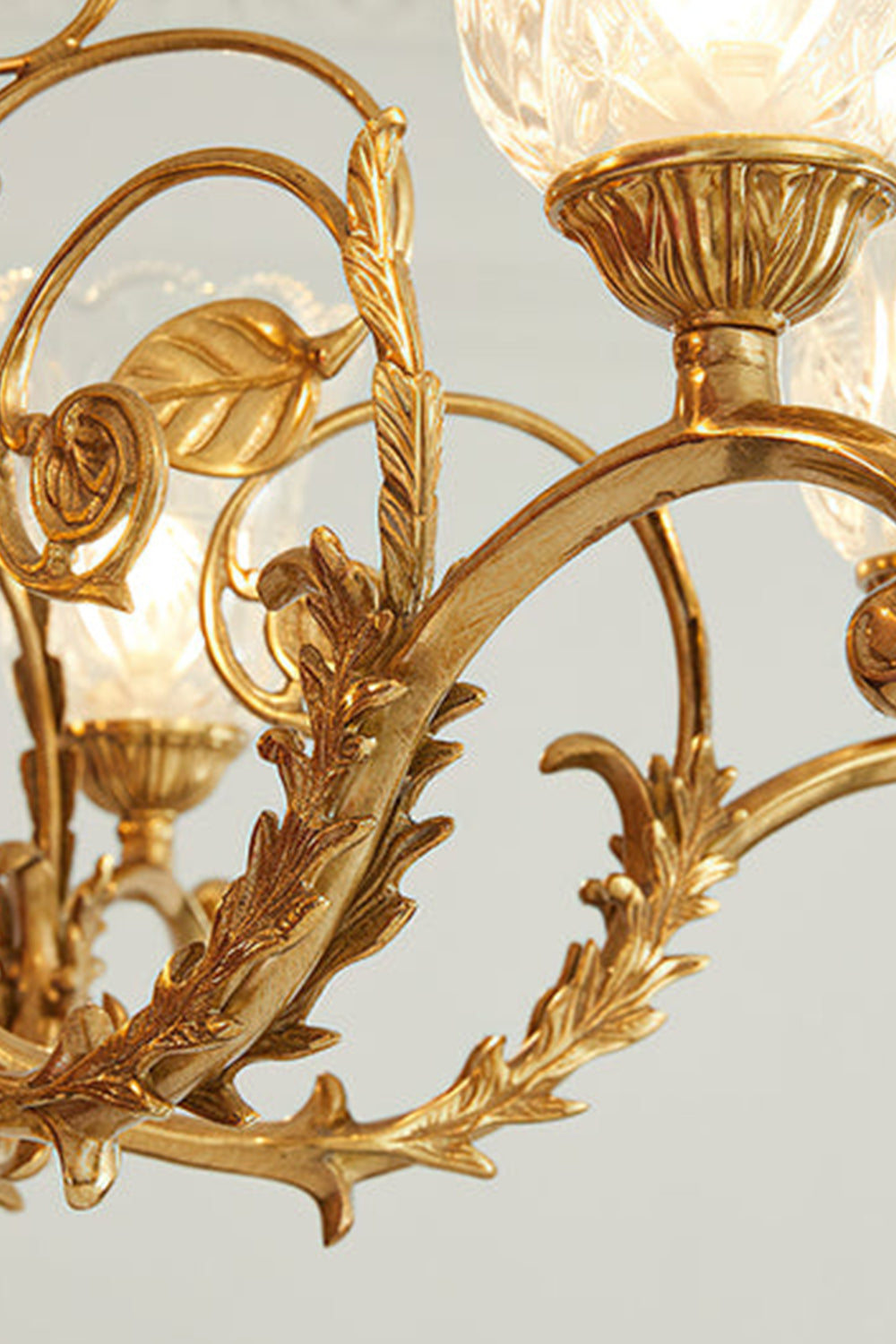 Beatrix Acanthus Leaf Chandelier | Ornate Brass and Frosted Carved Glass | Detailed shot of the intricate acanthus leaf relief and baroque scrollwork along the polished gold arms | Samu Lamp