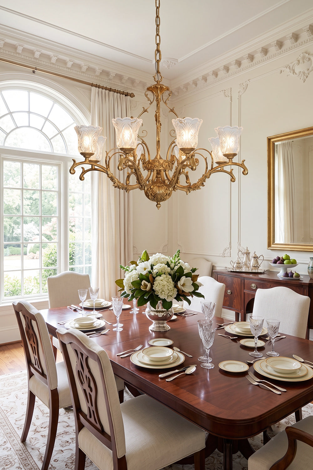 Beatrix Acanthus Leaf Chandelier | Ornate Brass and Frosted Carved Glass | Positioned over a long mahogany dining table with high-backed upholstered chairs next to a large arched window | Samu Lamp