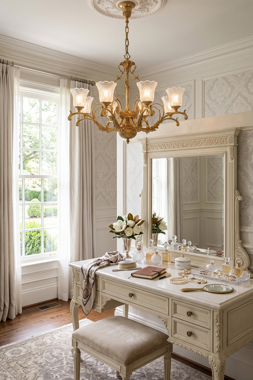 Beatrix Acanthus Leaf Chandelier | Ornate Brass and Frosted Carved Glass | Styled above an elegant white dressing vanity table with a round mirror and matching stool in a bedroom | Samu Lamp